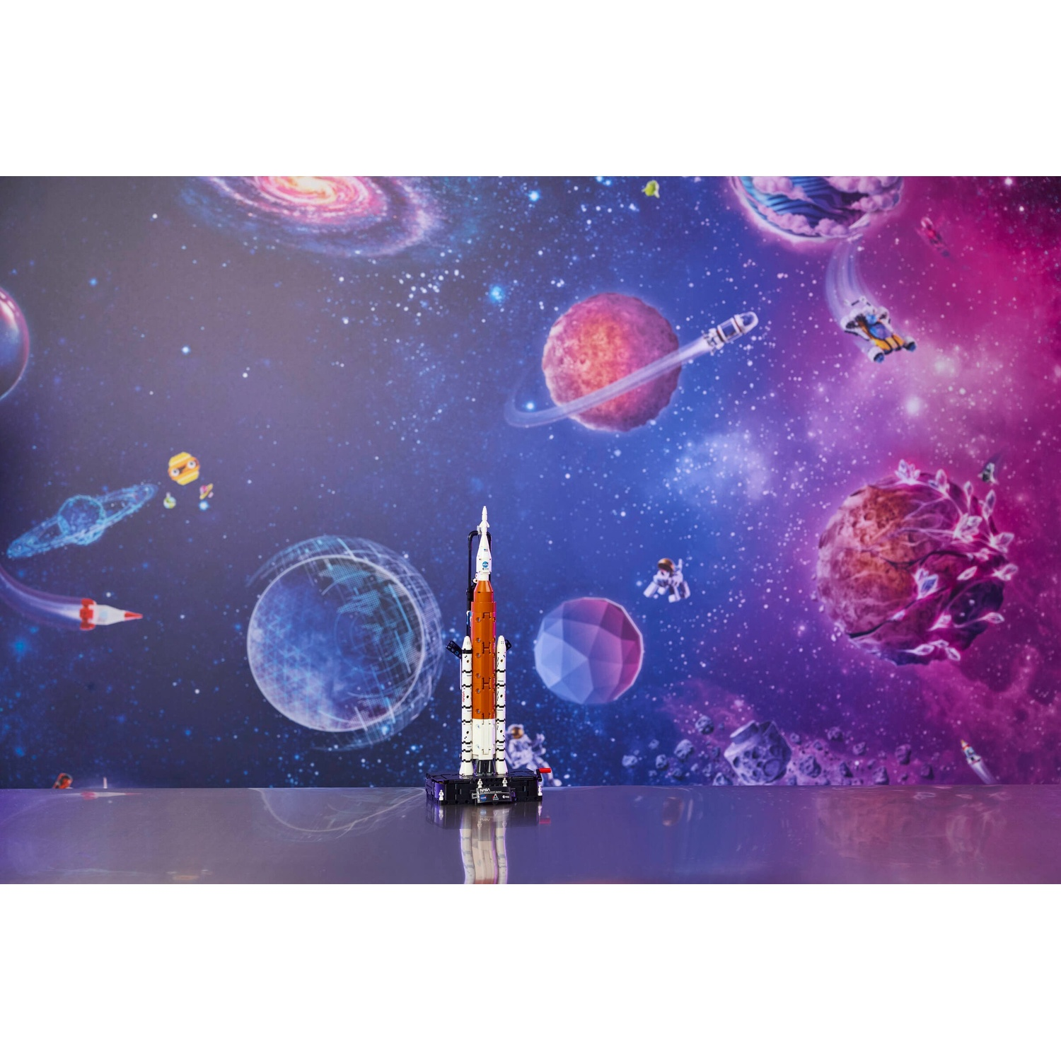 Un modello di razzo Lego si erge di fronte a una carta da parati spaziale colorata con pianeti.