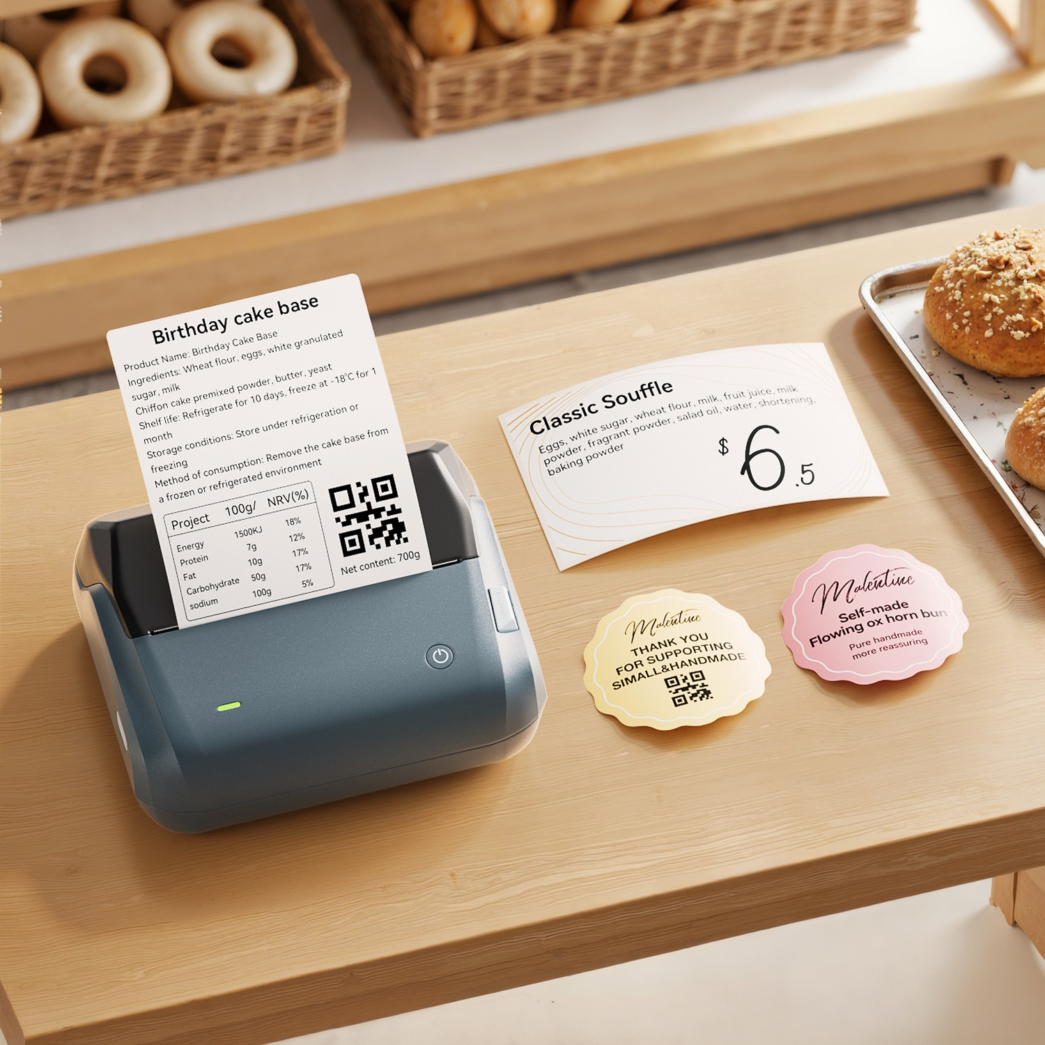 Portable printer on wooden table with printed label, souffle price tag, and baked pastries nearby.