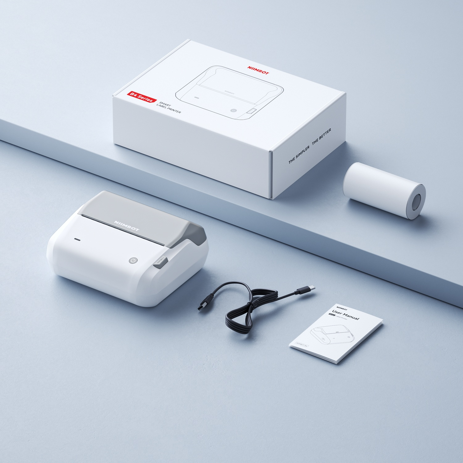 A white Niimbot B4 label printer with box, paper roll, USB cable, and manual on a light blue background.