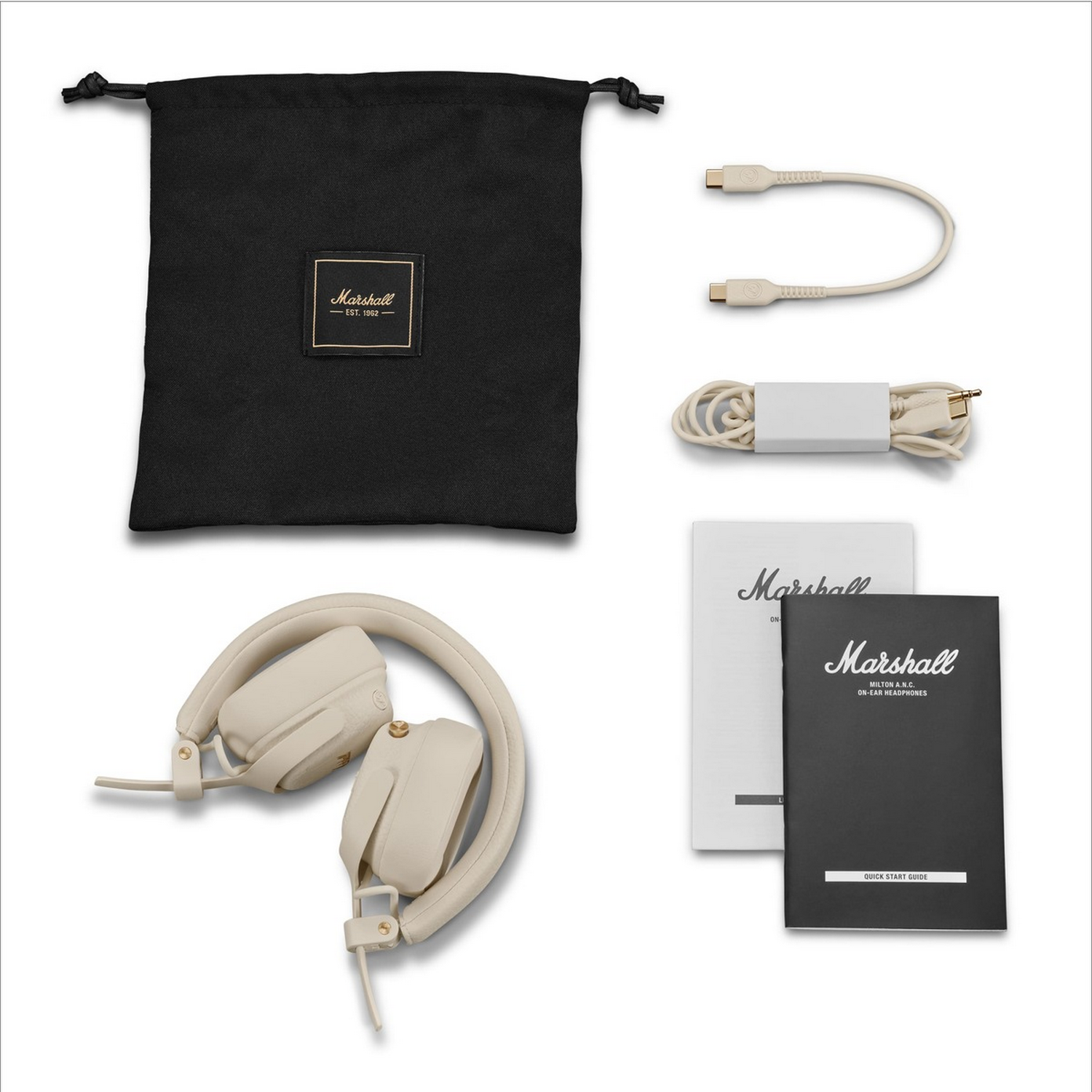 Auriculares crema Marshall, bolsa negra, cables y manuales de usuario sobre un fondo blanco.
