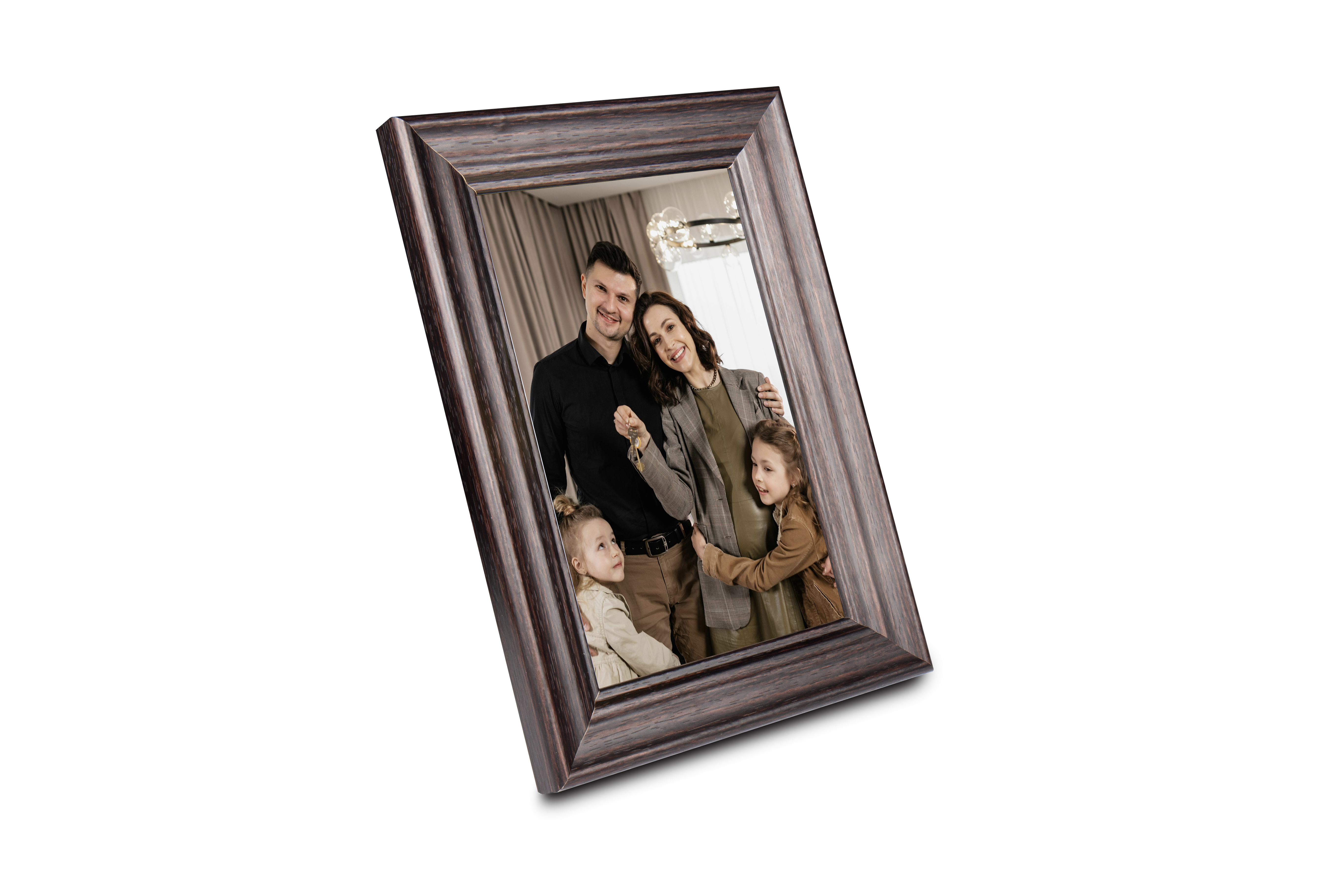 Eine Familie mit zwei Kindern steht lächelnd in einem dunklen Holzrahmen und hält Schlüssel in die Kamera.