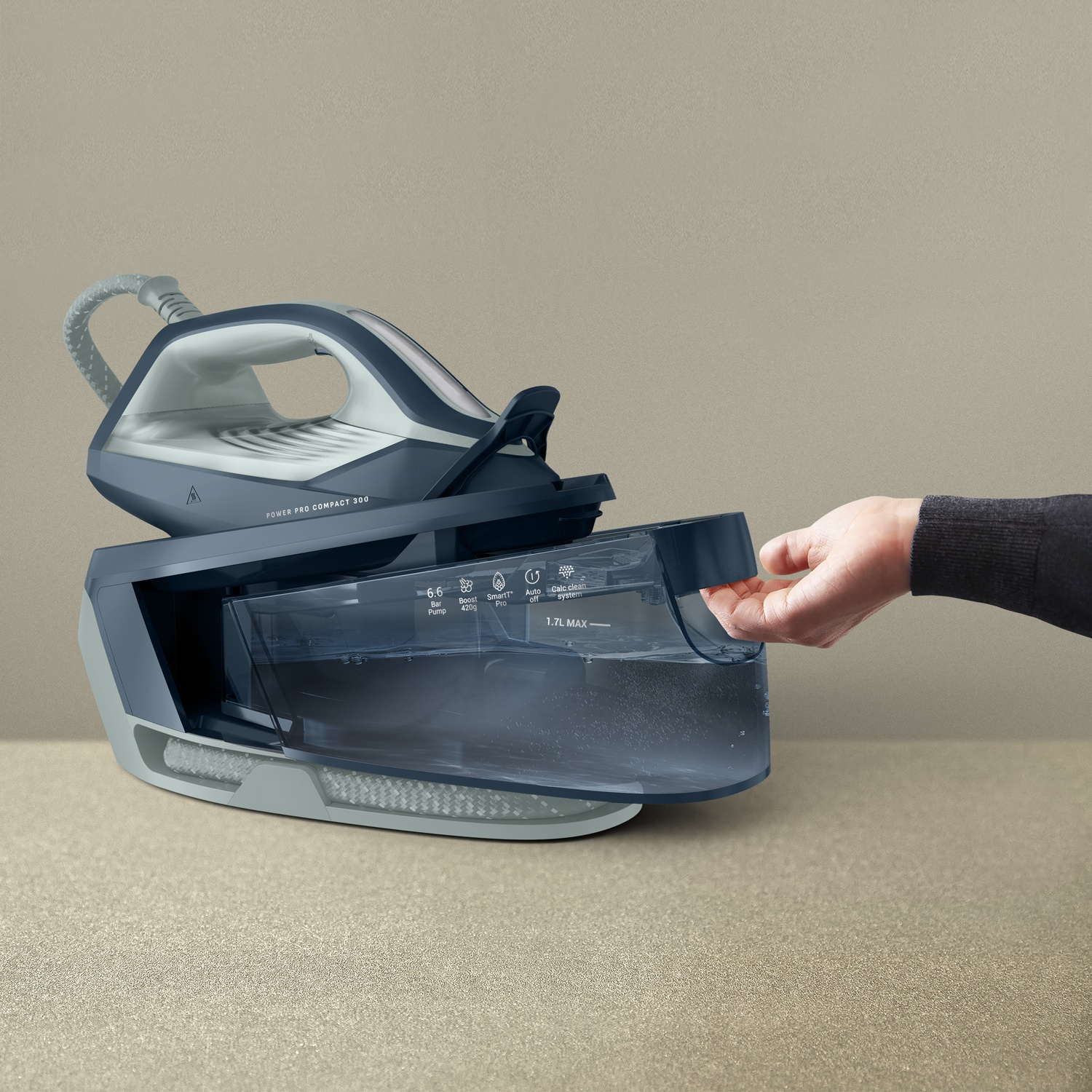 A hand pulls out the water tank of a blue steam generator iron.