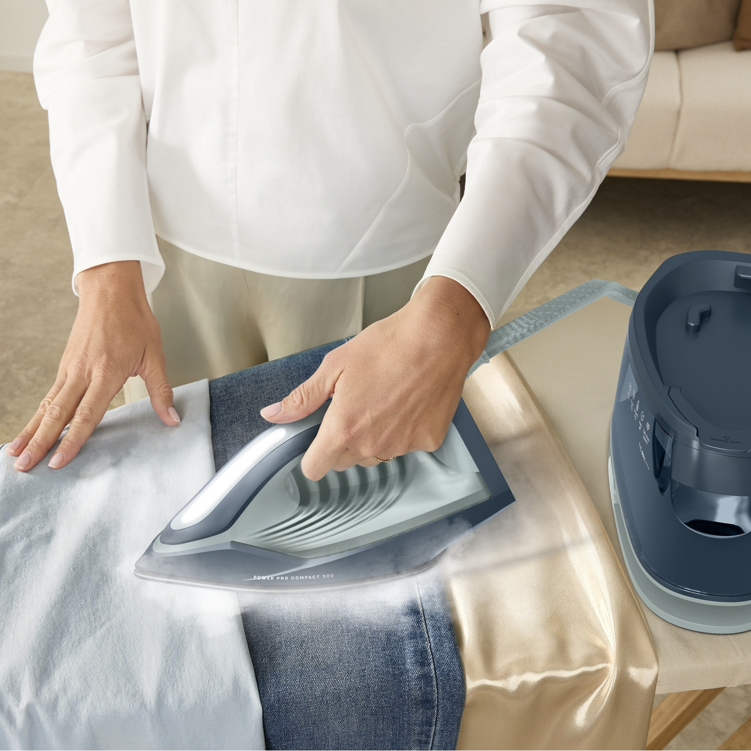 A person ironing clothes on an ironing board using a blue steam generator iron.