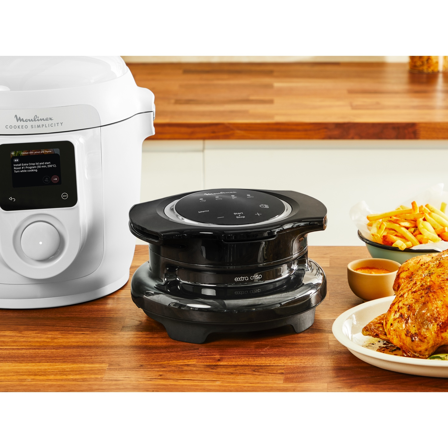 Moulinex koker en Extra Crisp deksel op houten tafel met geroosterde kip en friet.
