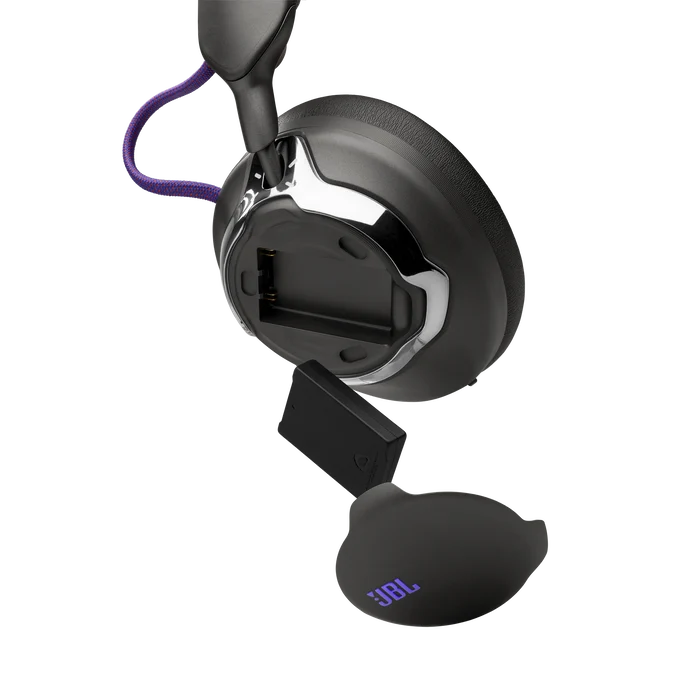 Auriculares JBL negros con un compartimento de batería abierto y batería extraíble sobre fondo negro.
