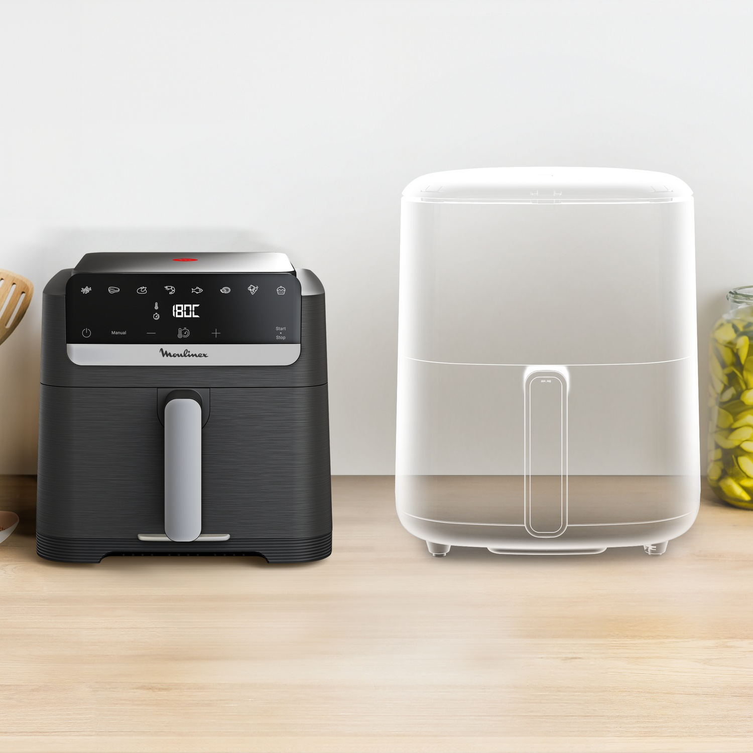 Een zwarte Moulinex heteluchtfriteuse staat naast een doorzichtige wireframe-omlijn van hetzelfde apparaat op een houten blad.
