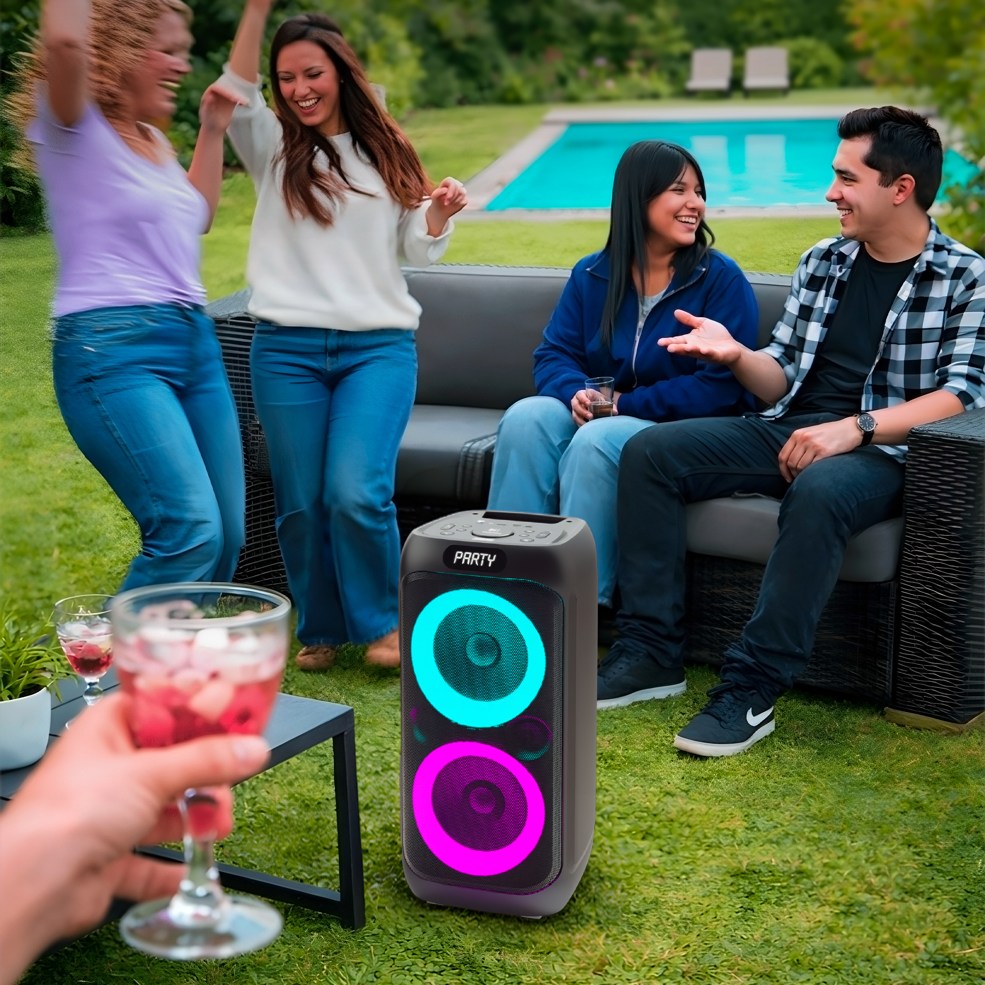 Amigos de fiesta en un jardín cerca de una piscina con música de un altavoz luminoso.