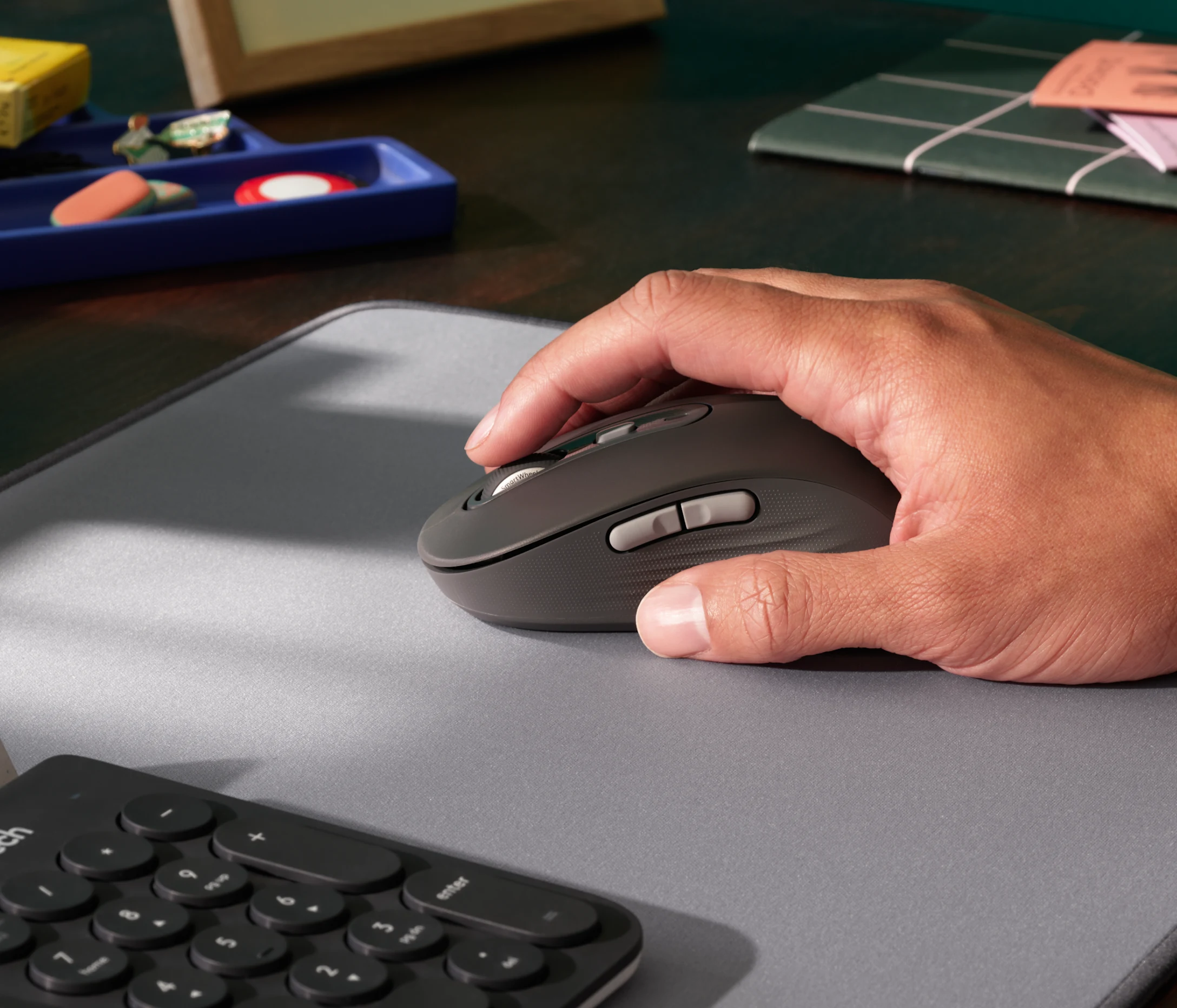 Une main utilise une souris d'ordinateur grise sur un tapis gris.