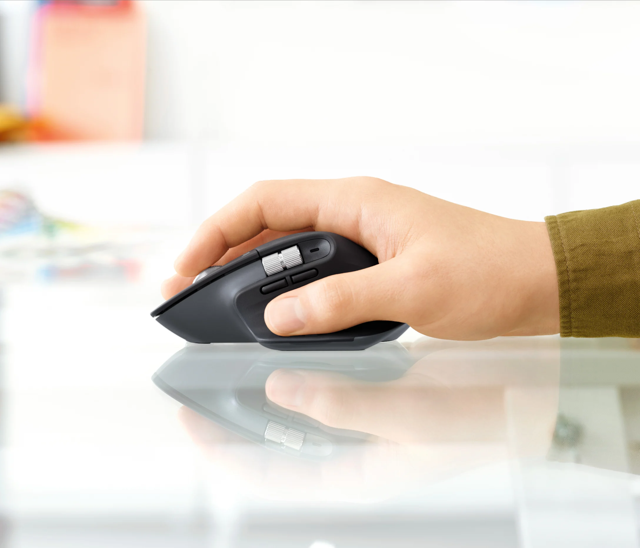Una mano che tiene un mouse per computer ergonomico nero su una superficie lucida.