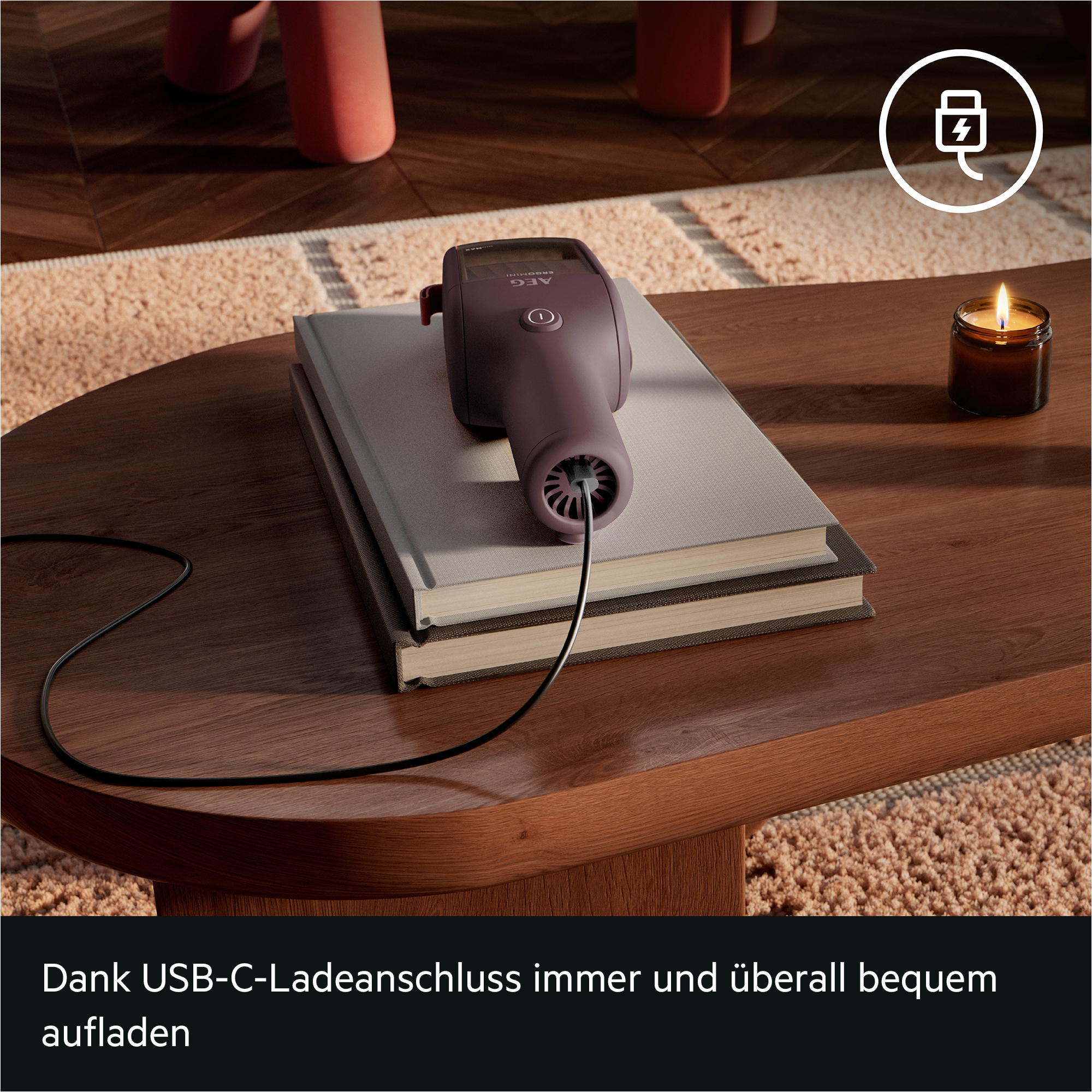 Ein violetter Handstaubsauger lädt mit einem USB-C-Kabel auf Büchern auf einem Holzbeistelltisch.