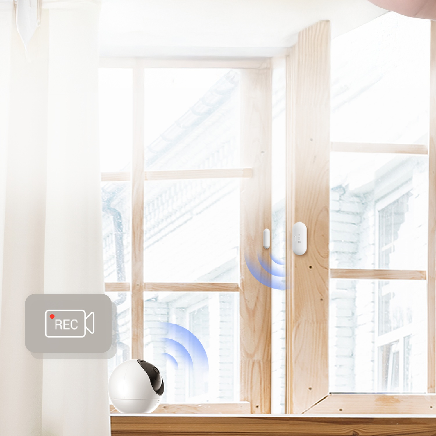 A white security camera and window sensor sit on a sill before a window, linked by blue signal waves.