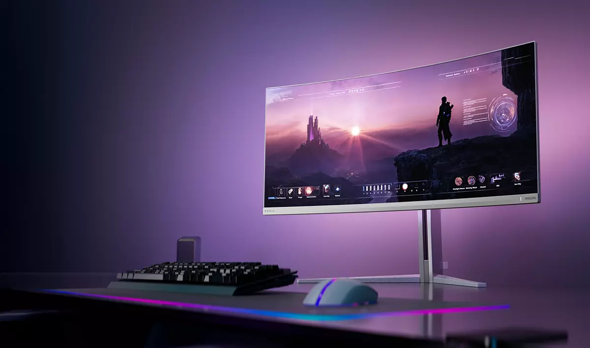 Ein geschwungener Gaming-Monitor zeigt eine Fantasy-Landschaft auf einem Schreibtisch mit Tastatur und Maus.