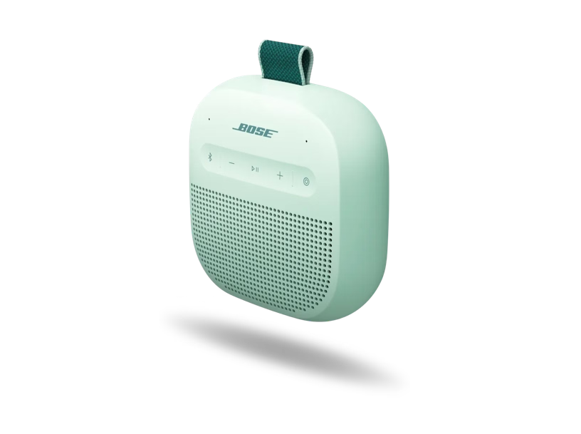Ein mintgrüner tragbarer Bose-Bluetooth-Lautsprecher mit einer grünen Schlaufe vor schwarzem Hintergrund.