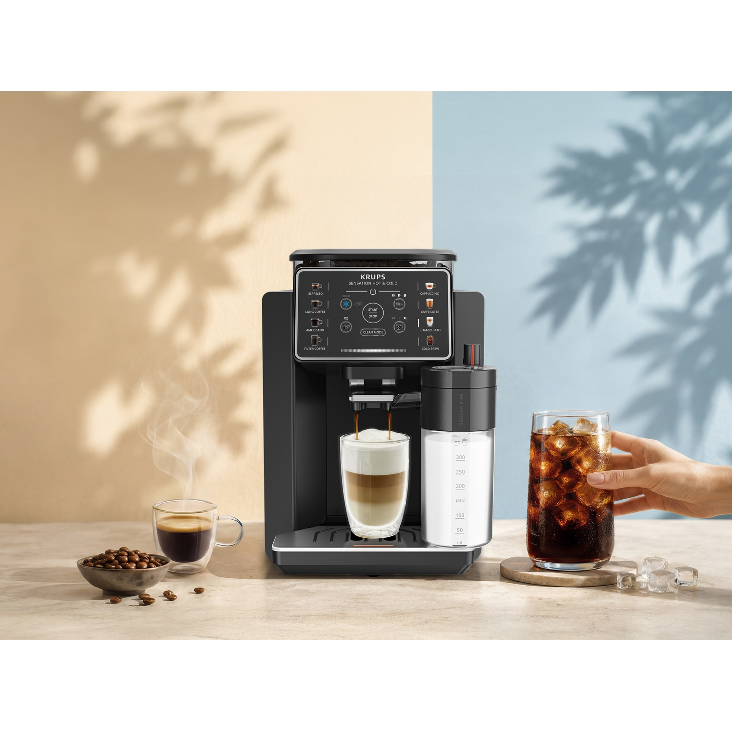 Machine à café Krups sur une table avec tasse d'espresso, réservoir de lait et verre de café glacé.