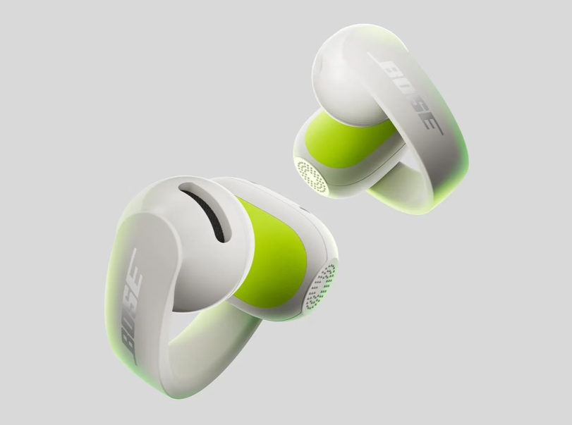 Weiße und hellgrüne kabellose Bose Open-Ear-Ohrhörer vor neutralem grauem Hintergrund.