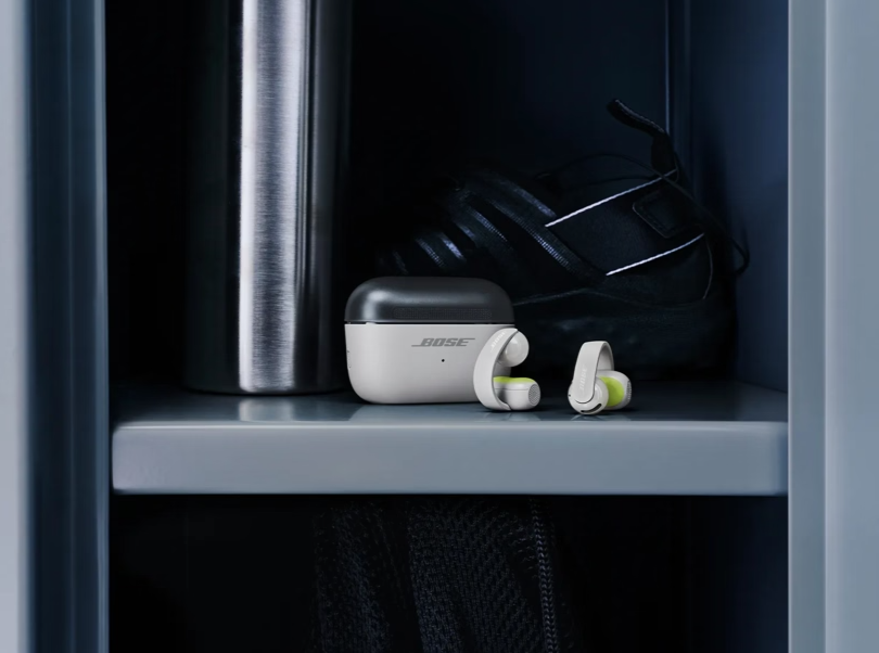 Bose-Ohrhörer und Ladeetui auf einem Spindregal mit Metallflasche und Schuh.