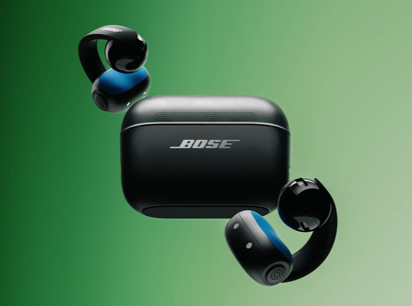 Schwarze Bose-Ohrhörer mit blauem Akzent und Ladecase vor grünem Hintergrund.