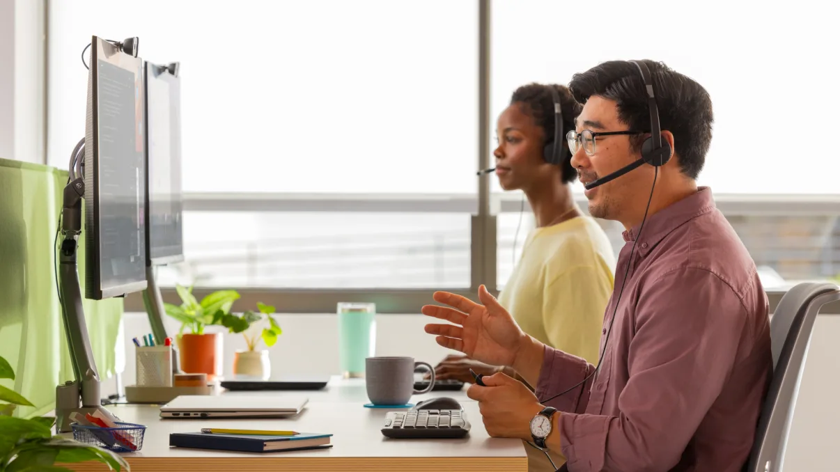 Due agenti del servizio clienti con cuffie che lavorano al computer.