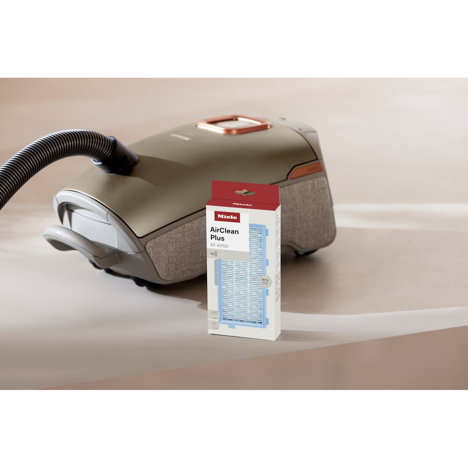 Een beige Miele stofzuiger met een bijpassende AirClean Plus filterdoos op de voorgrond.