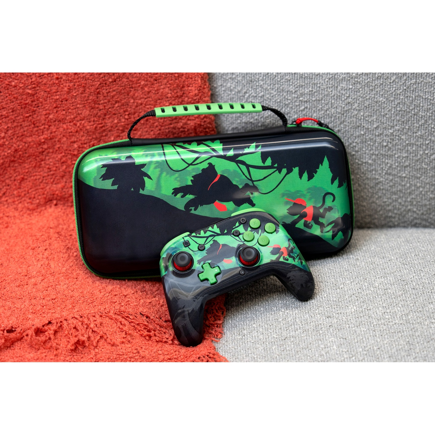 A jungle-themed gaming controller and matching carrying case sit on an orange and grey couch.