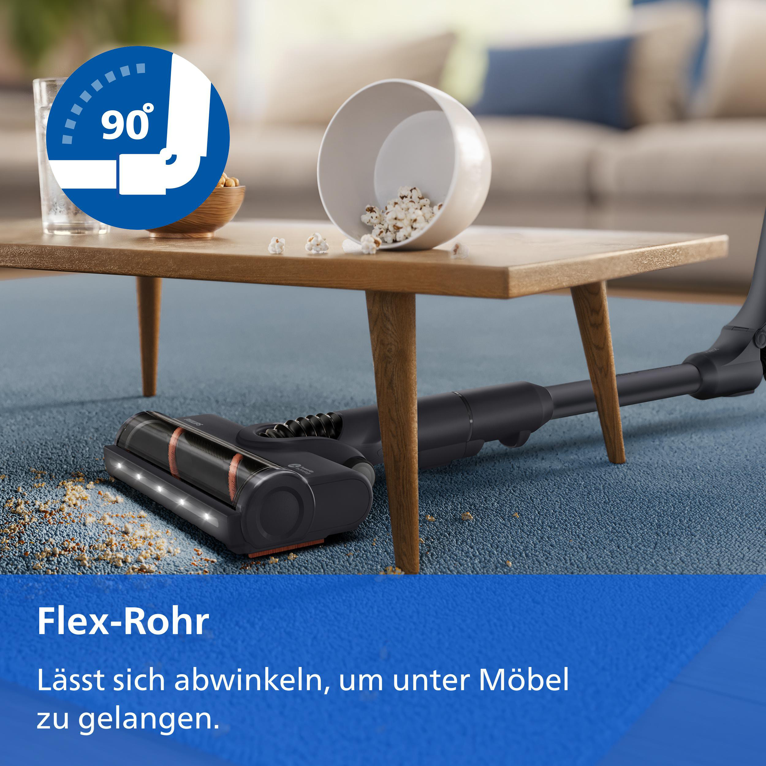 Ein Staubsauger mit flexiblem Rohr reinigt unter einem Couchtisch auf einem Teppich.