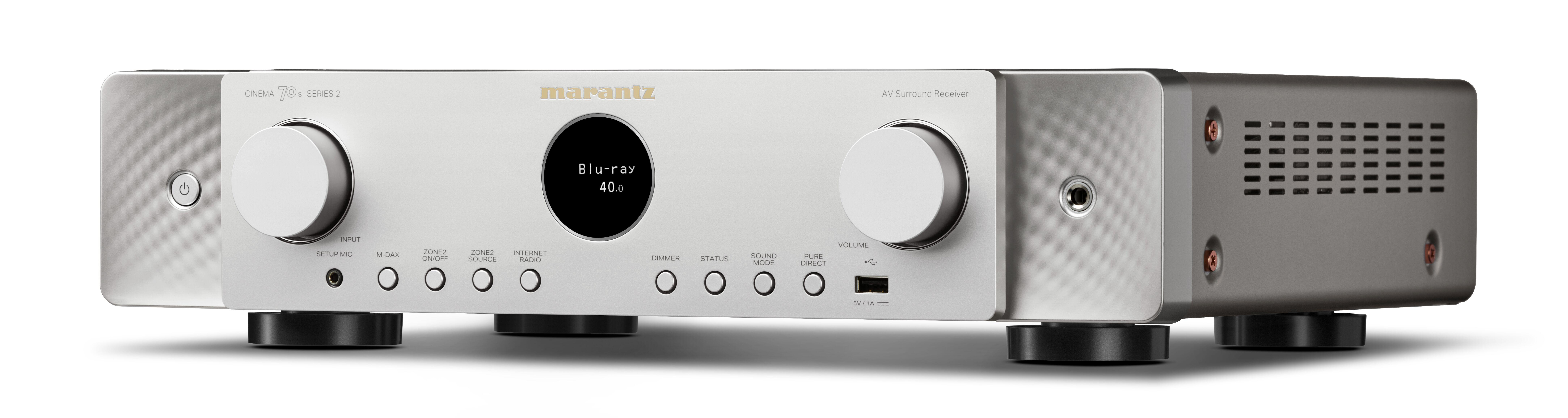 Silberner Marantz AV-Surround-Receiver mit zentralem runden Display und zwei großen Reglern auf weißem Hintergrund.