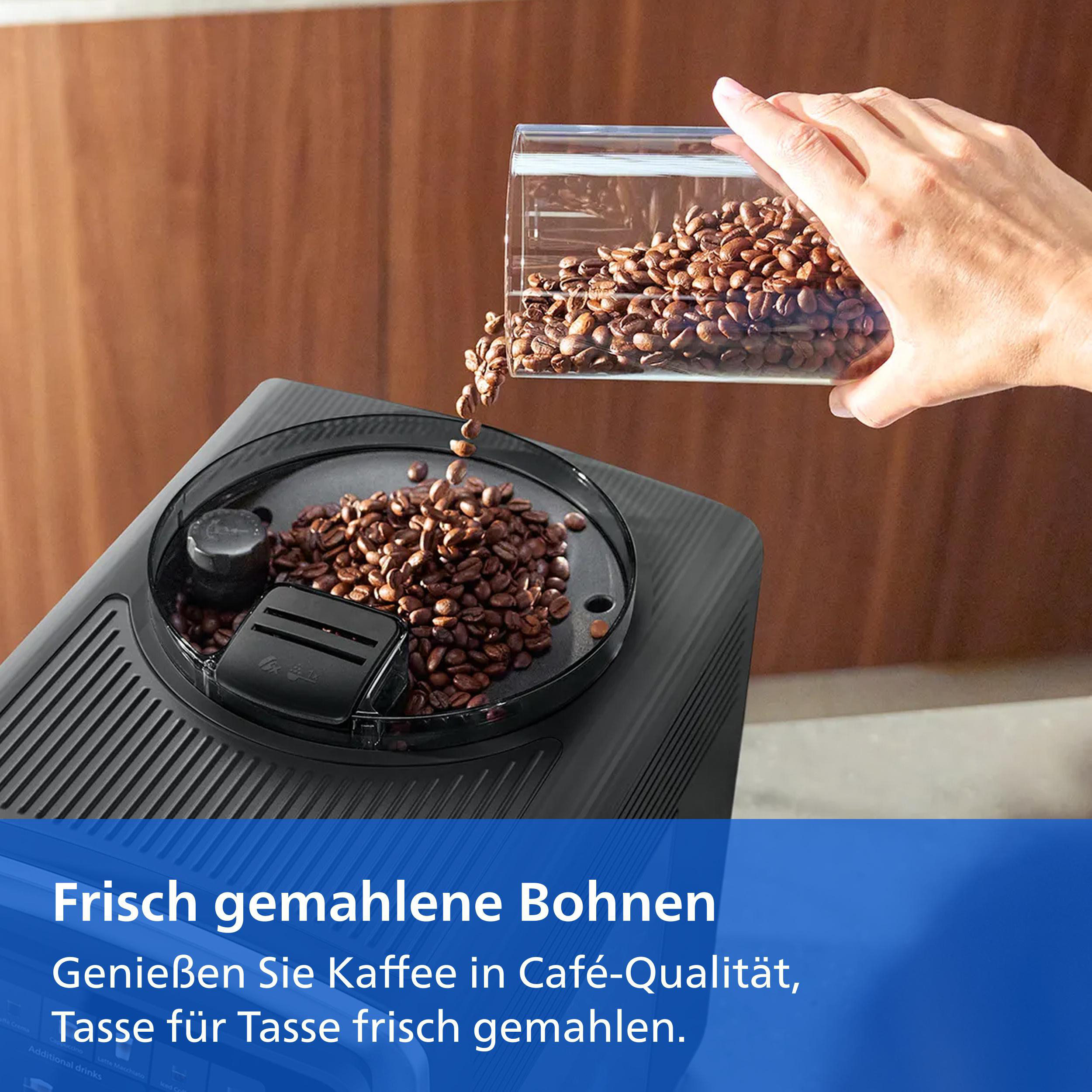 Eine Hand schüttet Kaffeebohnen aus einem Behälter in den Mahlwerksschacht einer Kaffeemaschine.