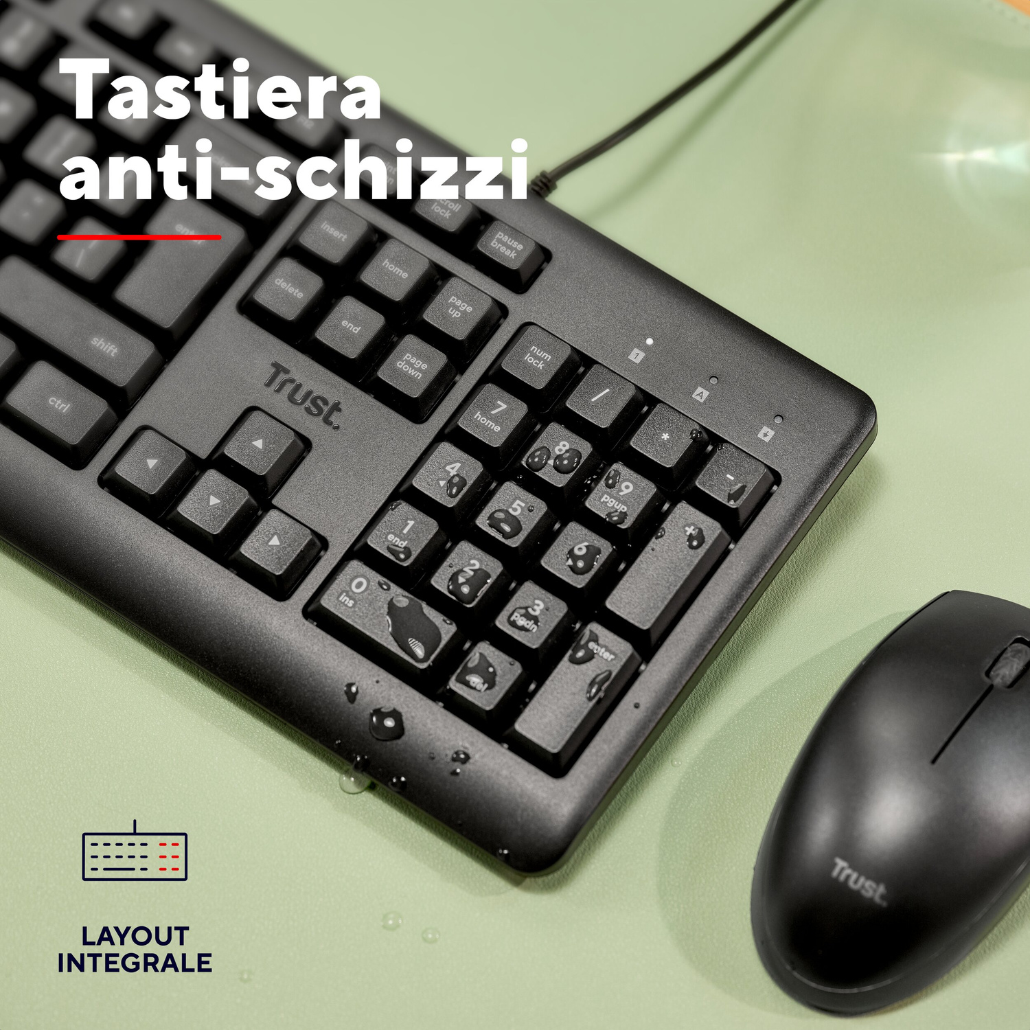 Tastiera e mouse neri Trust su superficie verde, con gocce d'acqua sui tasti.