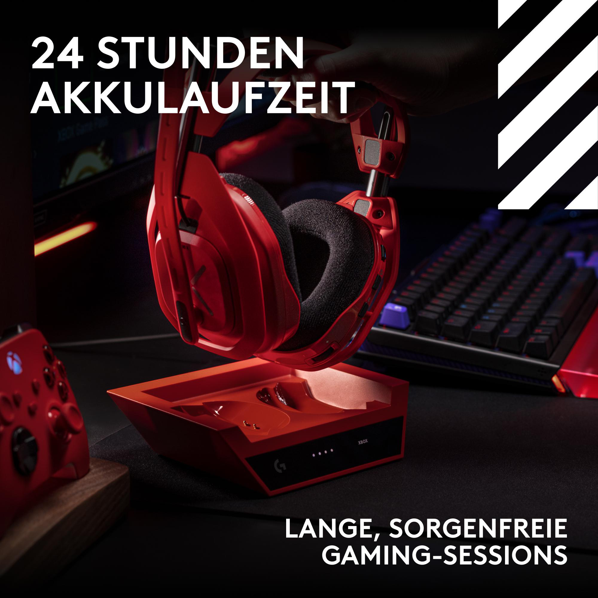Rotes Gaming-Headset über einer passenden Ladestation auf einem dunklen Tisch, mit Controller und Tastatur im Hintergrund.