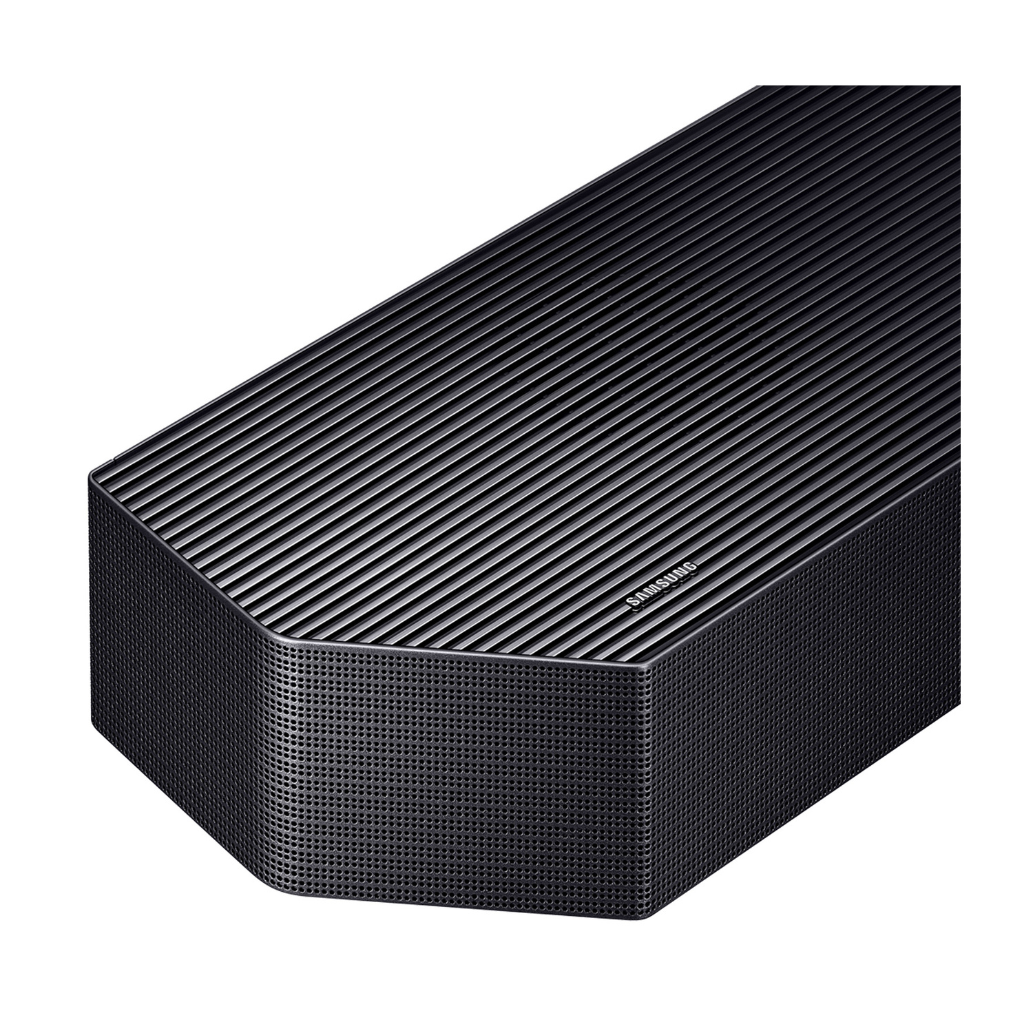 Primo piano di una soundbar Samsung scura con parte superiore scanalata e griglia metallica perforata.