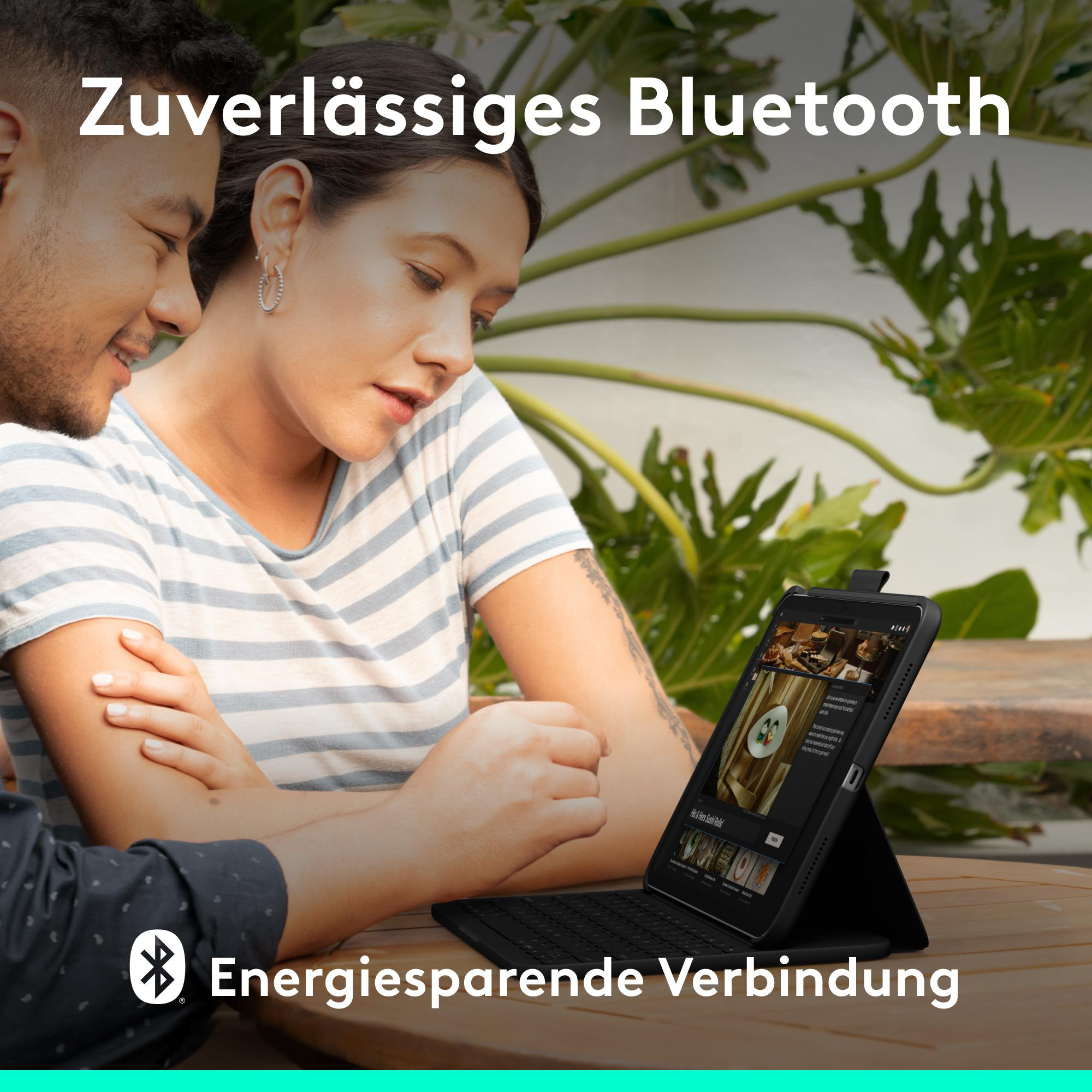 Ein Paar sieht auf eine Tablet-Tastatur im Freien.