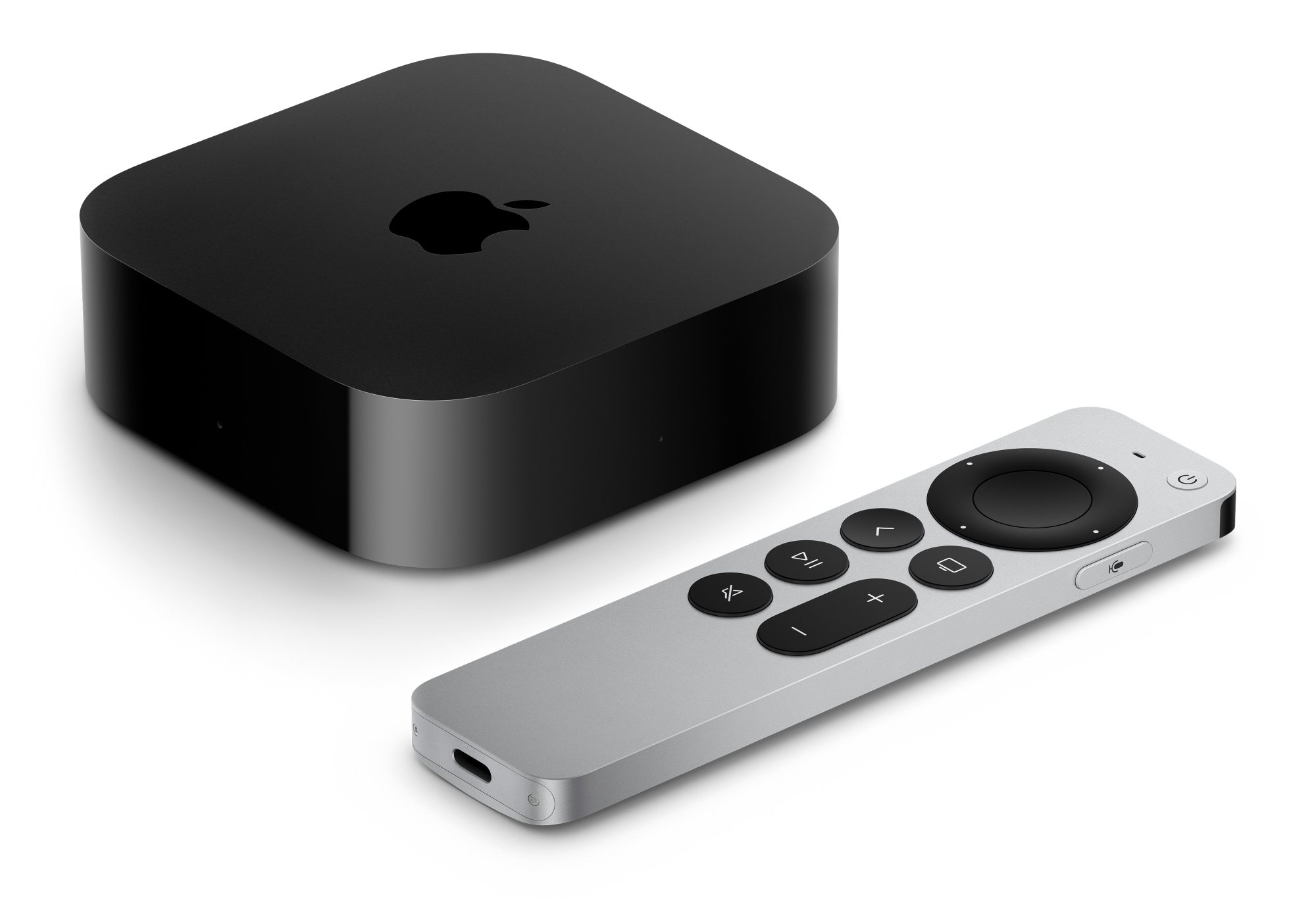 Czarne urządzenie Apple TV i srebrny pilot z czarnymi przyciskami na białej powierzchni.
