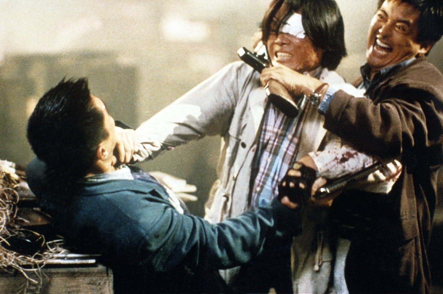 Drei Männer in einer gewaltsamen Konfrontation, einer mit Augenklappe und blutigem Hemd.