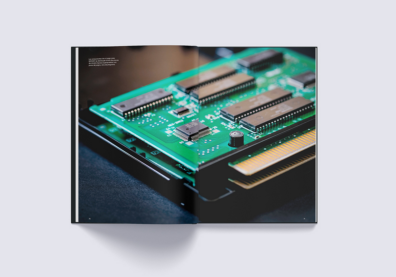 Un libro abierto muestra una foto de una placa de circuito verde con microchips y conectores.