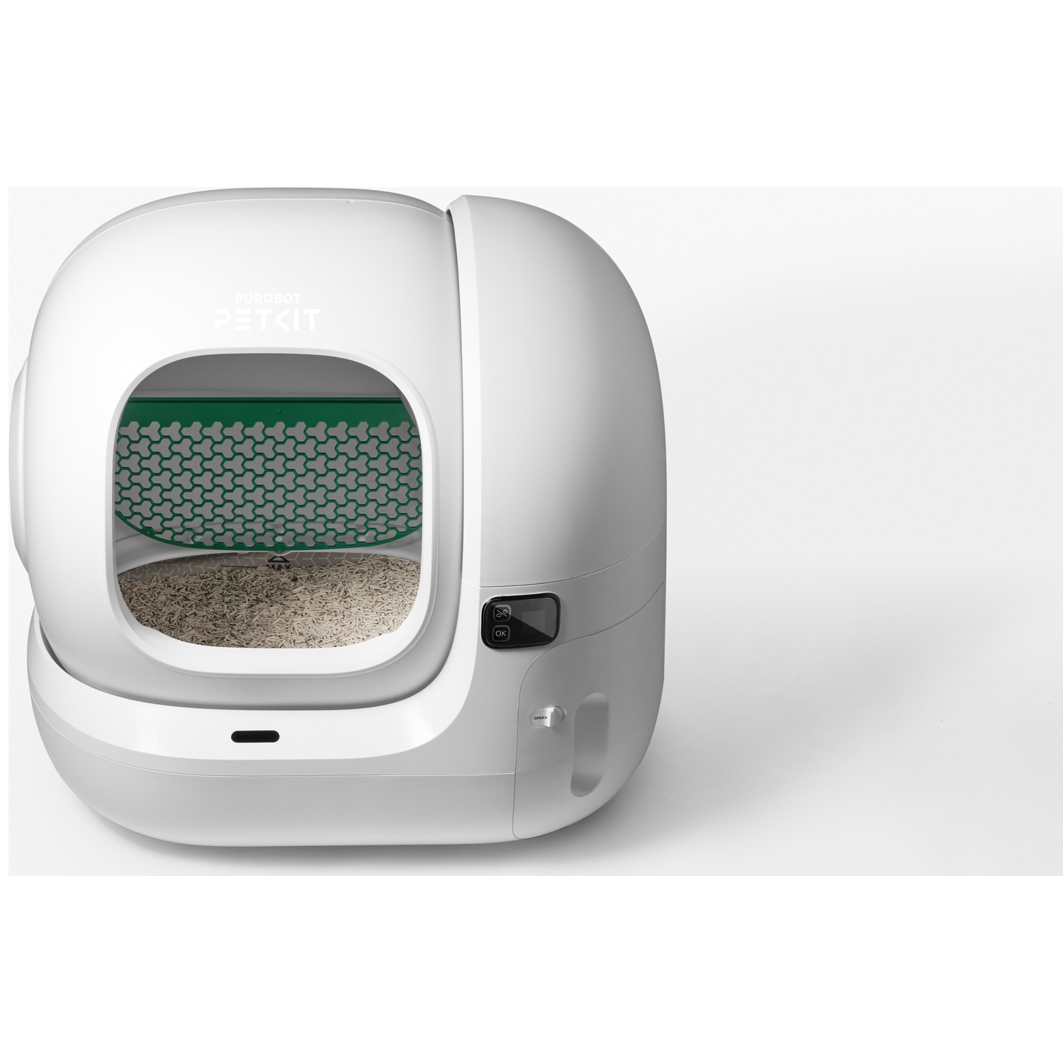 Un bac à litière automatique blanc pour chat avec de la litière et une grille verte à l'intérieur.