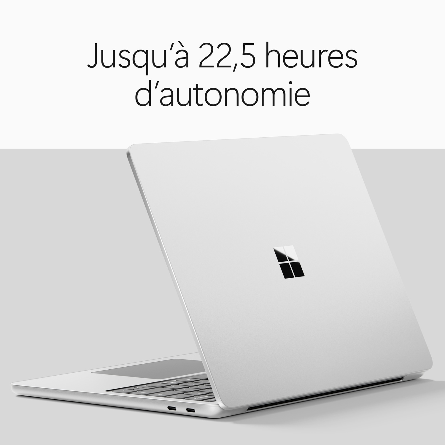 Un ordinateur portable argenté sur fond gris avec du texte.