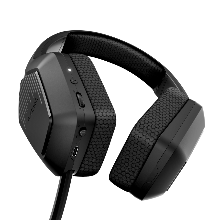 Unos auriculares de diadema para juegos negros con cojines de patrón de panal sobre fondo oscuro.