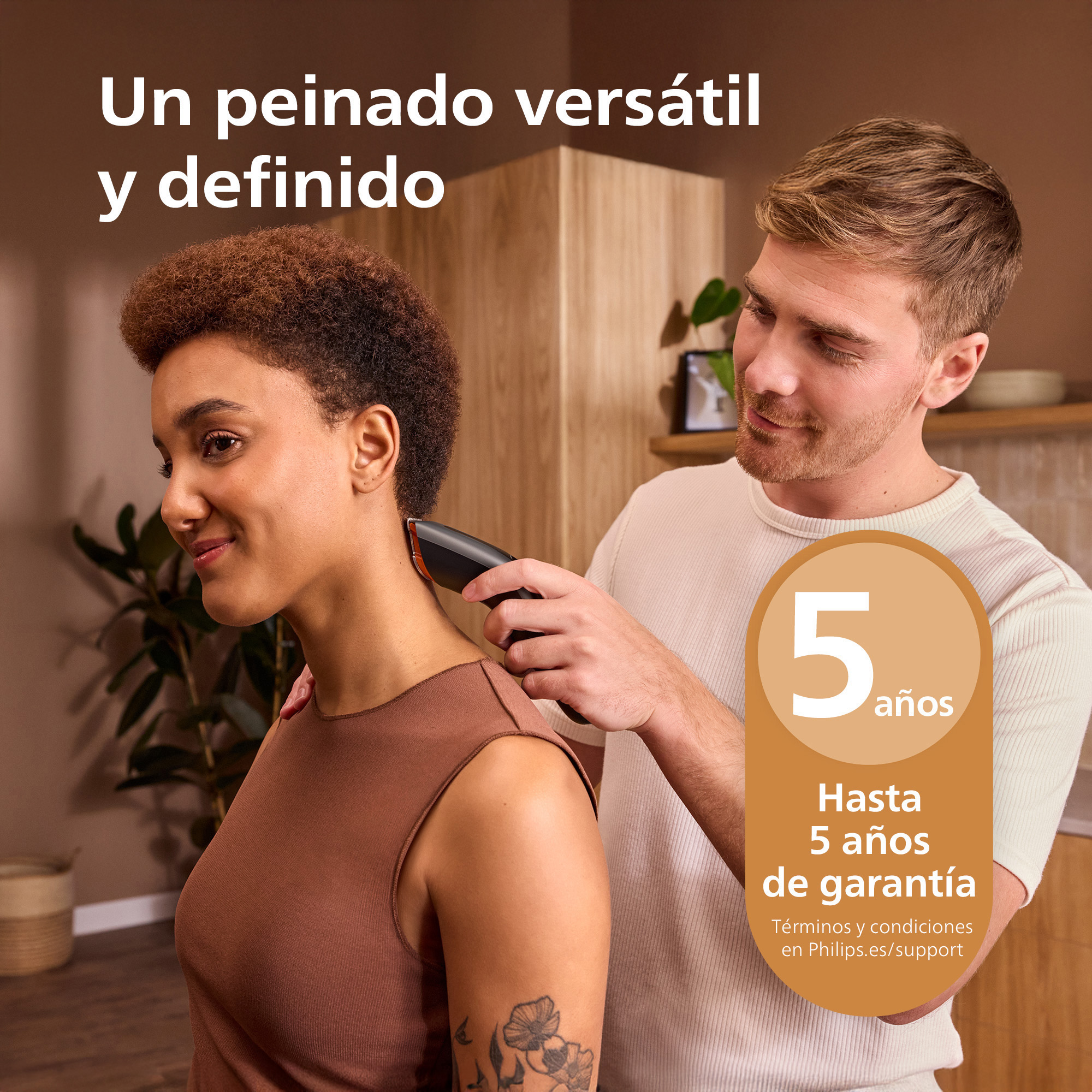 Un hombre corta el pelo corto de una mujer sonriente con una maquinilla.
