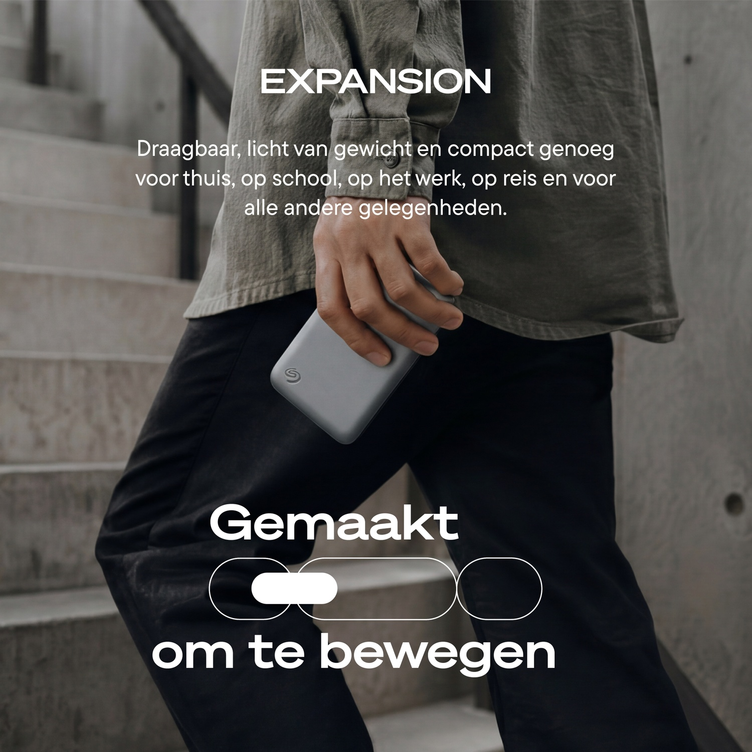 Person holding a compact gray external hard drive in front of stairs, with Dutch text overlay.