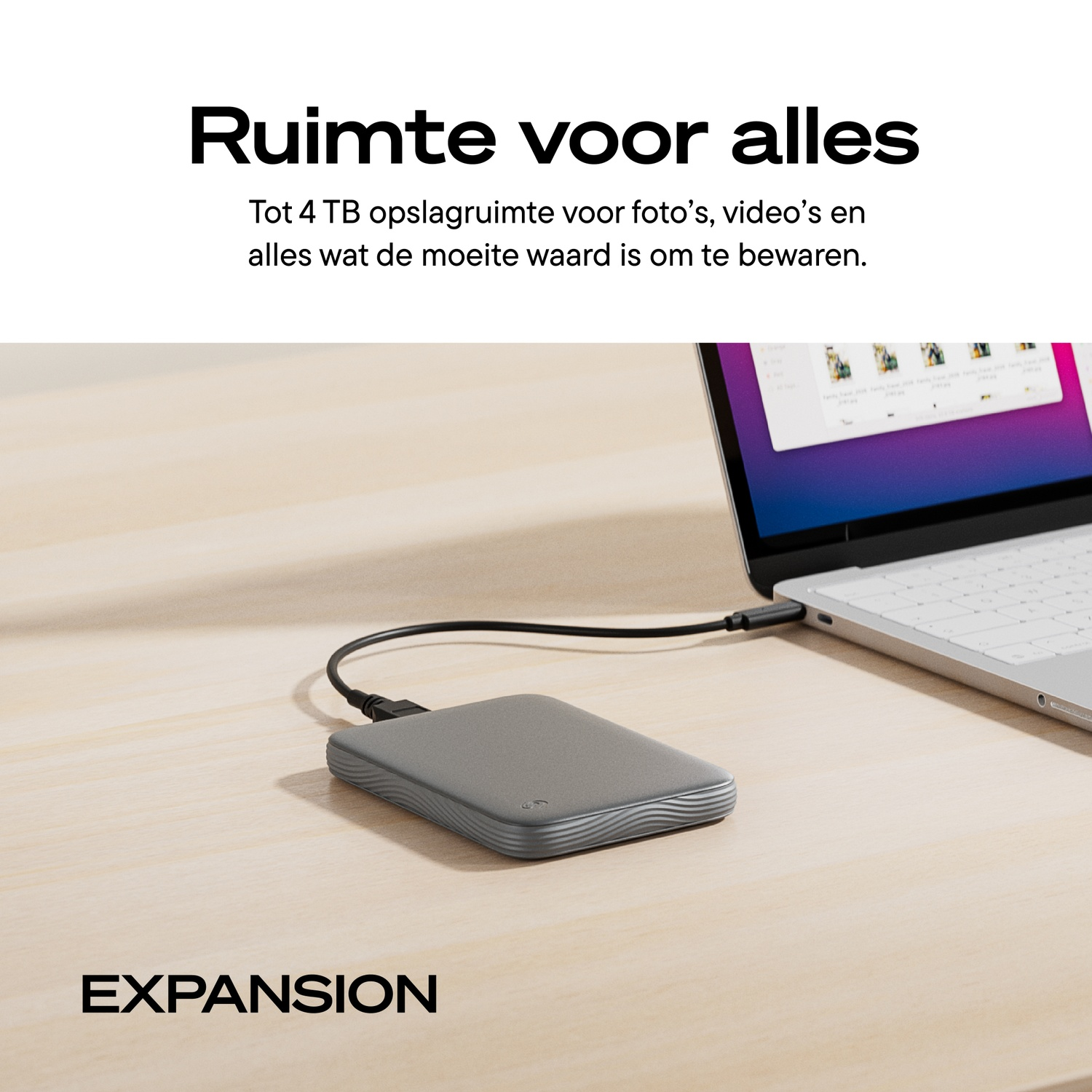 A grey external hard drive is connected via cable to a laptop on a wooden desk, with text at the top and bottom.