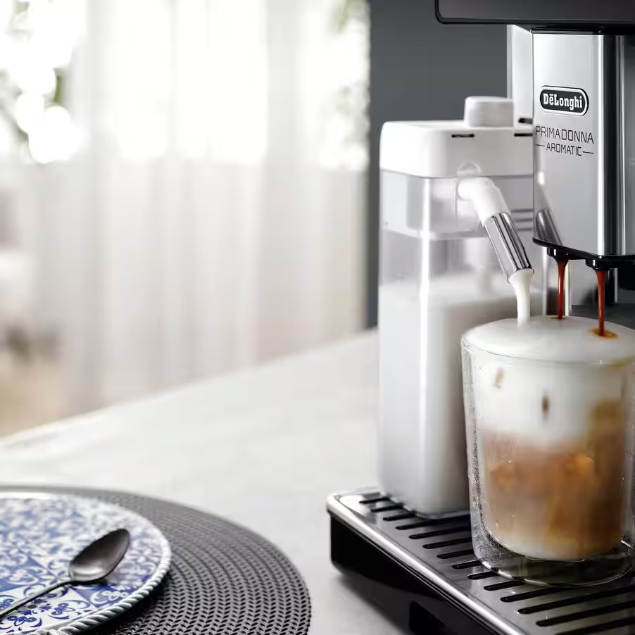Ekspres do kawy De'Longhi wlewa espresso i mleko do szklanki.