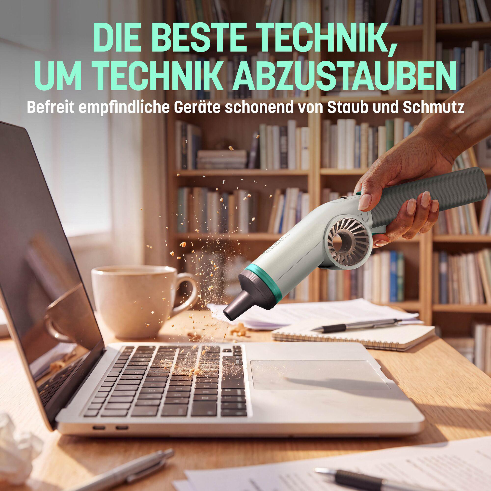 Eine Hand nutzt einen kleinen elektronischen Bläser, um Staub und Krümel von einer Laptop-Tastatur zu entfernen.