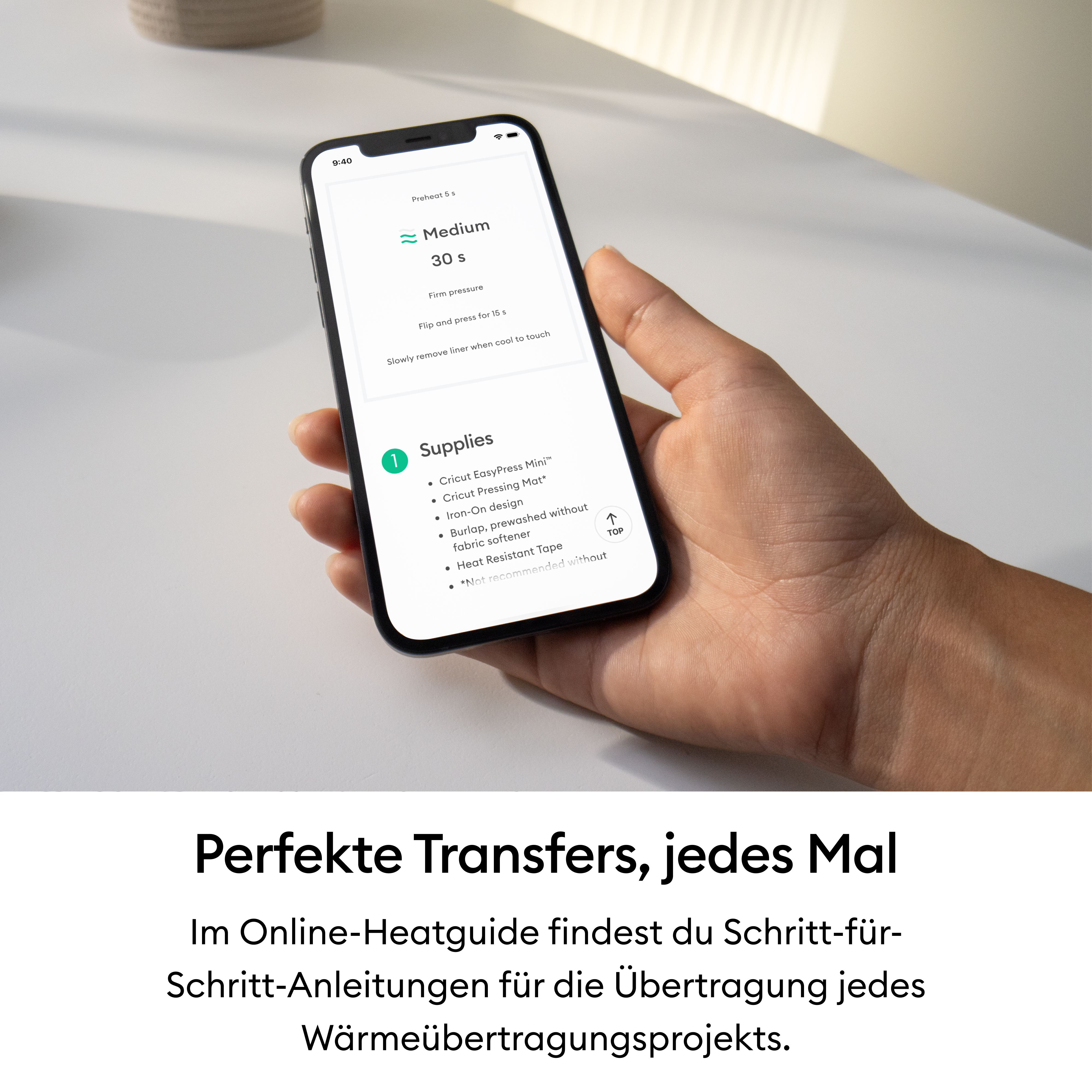 Eine Hand hält ein Smartphone mit einer Heatguide-App auf einem Tisch.
