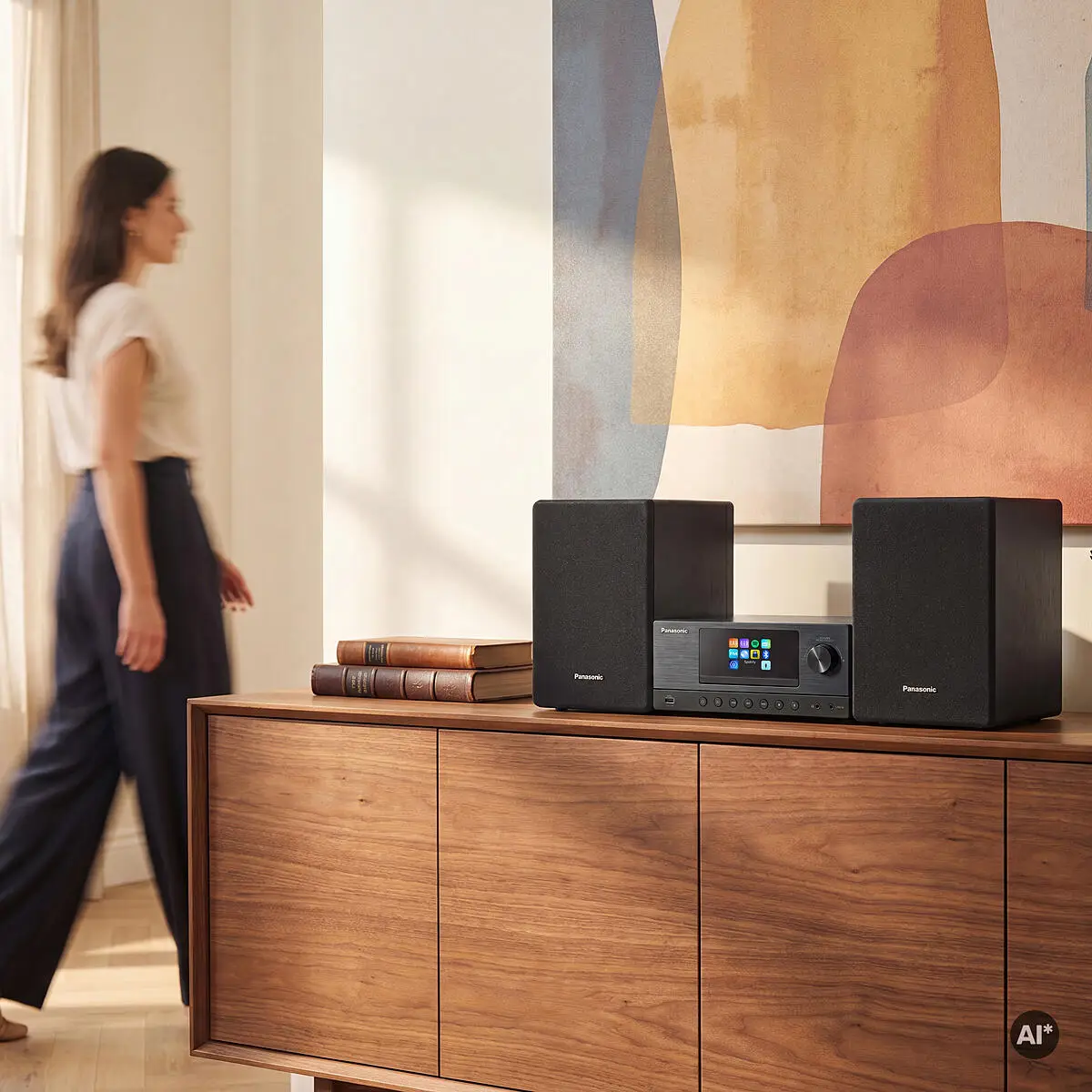 Egy nő elhalad egy fa szekrény mellett, amelyen egy Panasonic hifi van egy festmény előtt.
