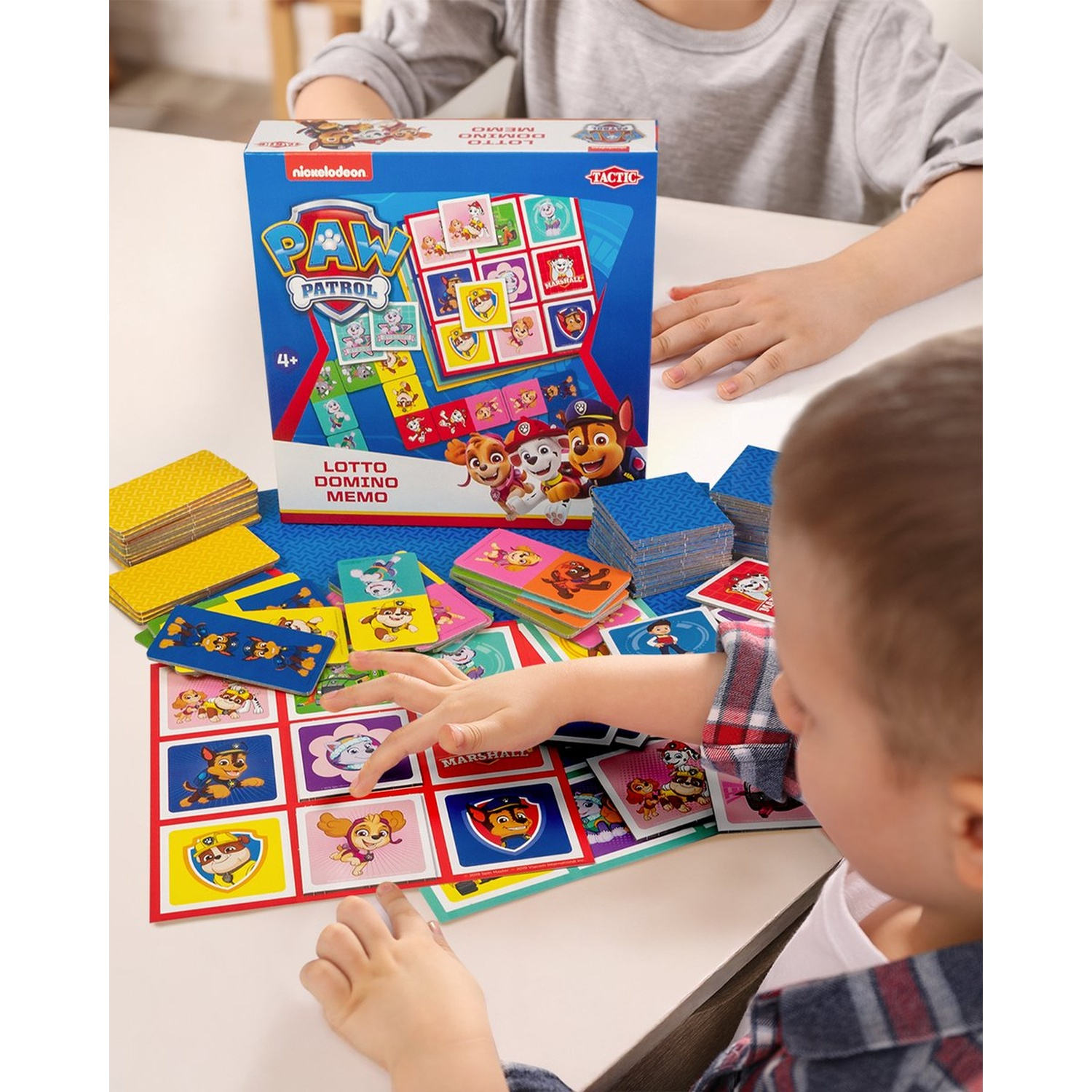 Children playing with a Paw Patrol lotto, domino and memo board game at a table.