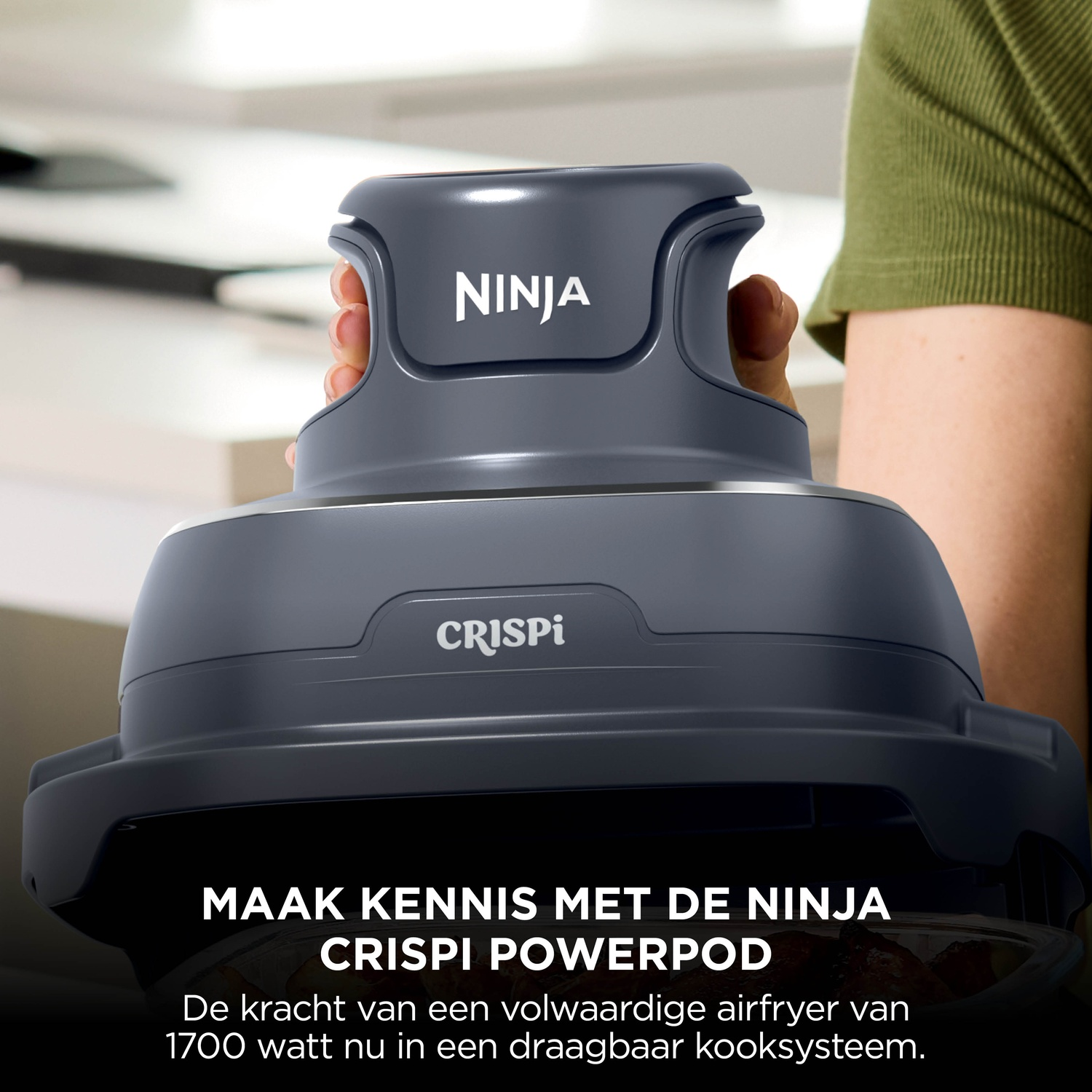 A person holds the grey Ninja Crispi Powerpod cooker, a portable 1700W airfryer system.