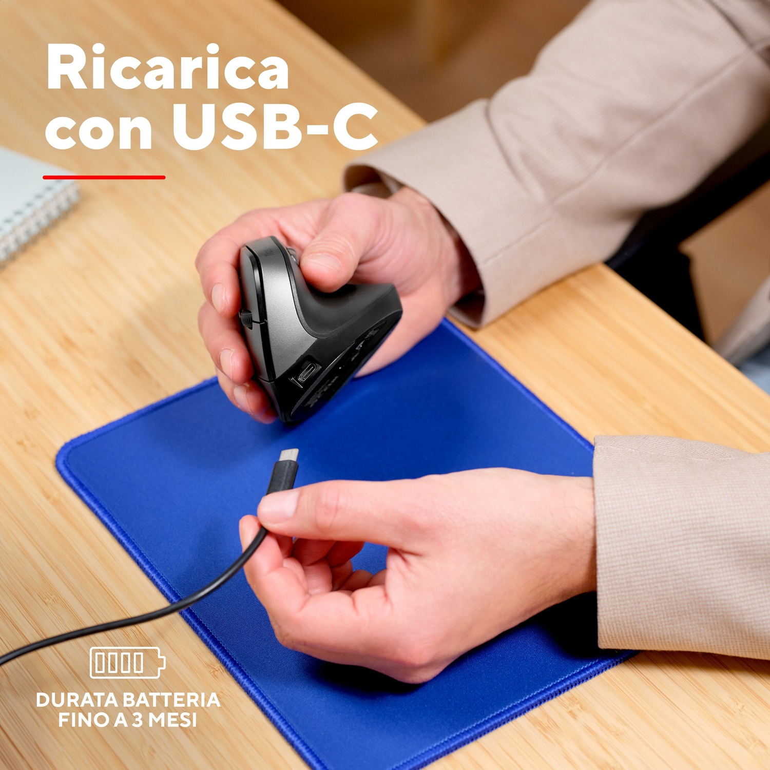 Una persona collega un cavo USB-C a un mouse verticale ergonomico su un tappetino blu.