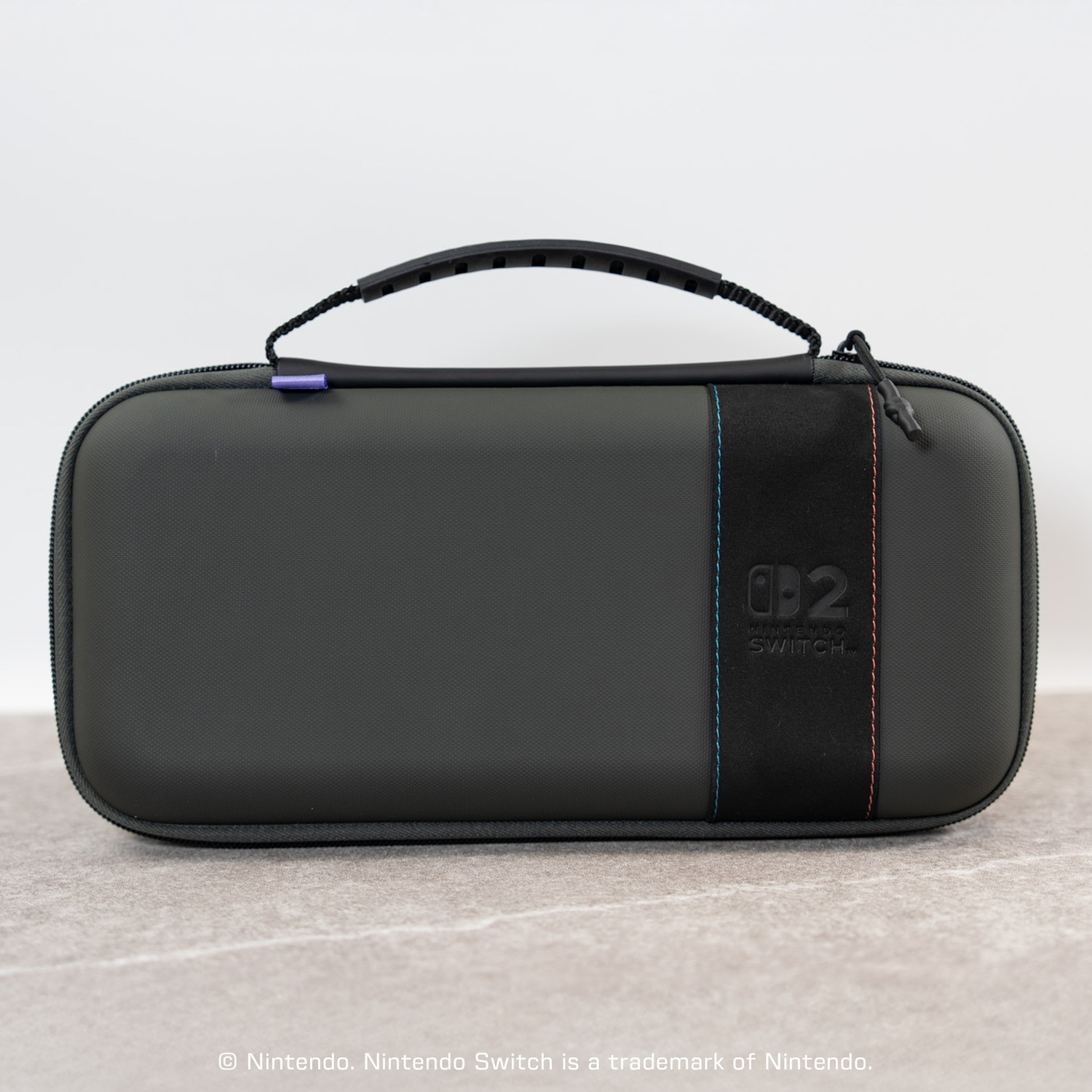 A gray Nintendo Switch carrying case with a handle and black accent stripe sits on a light surface.