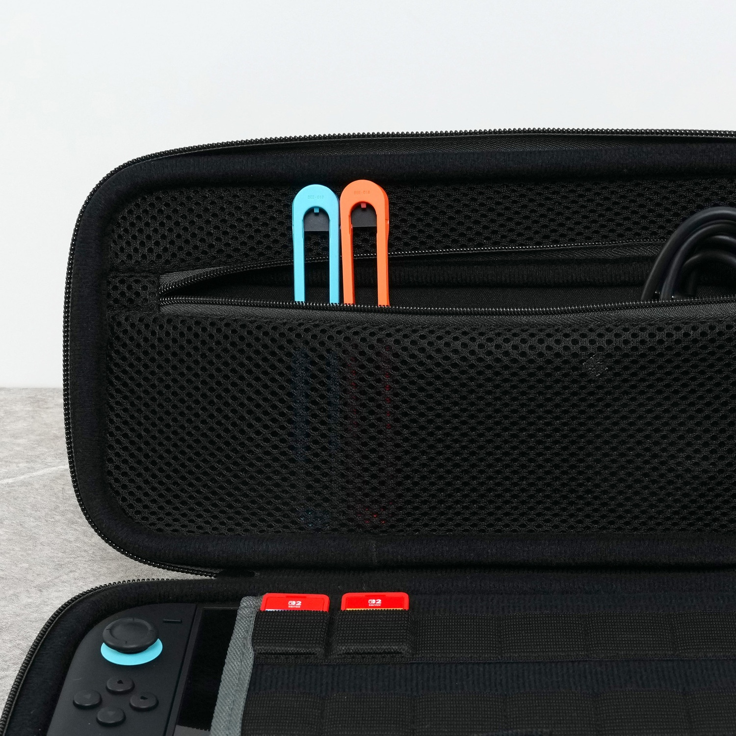 Black Nintendo Switch case with blue and orange joy-con straps in the mesh pocket.