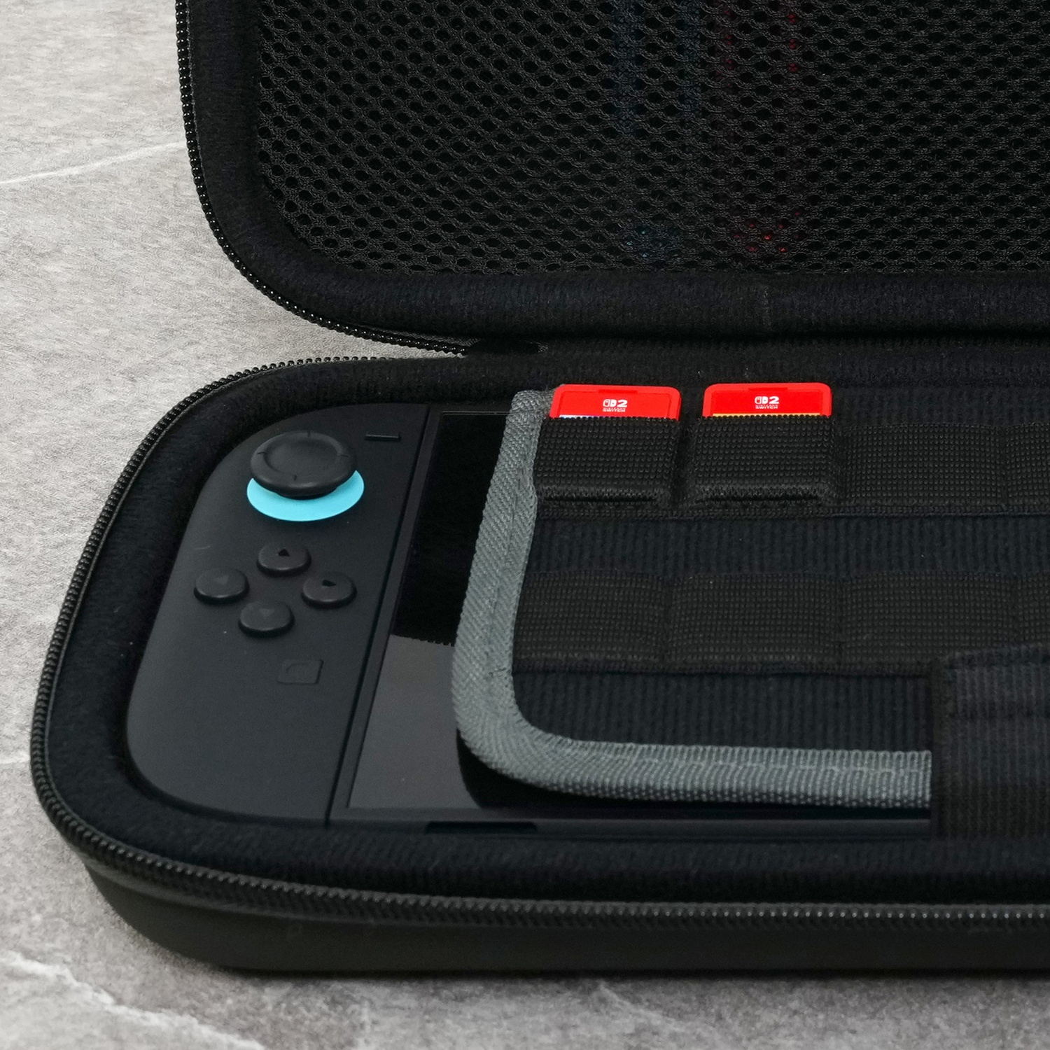 A black carrying case contains a console and two red game cards.